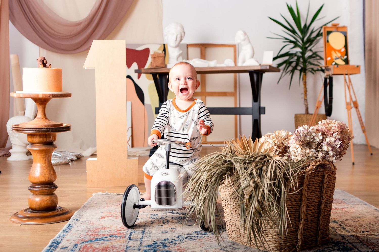A smiling child rides a vintage-style white pedal car near decorative home elements.