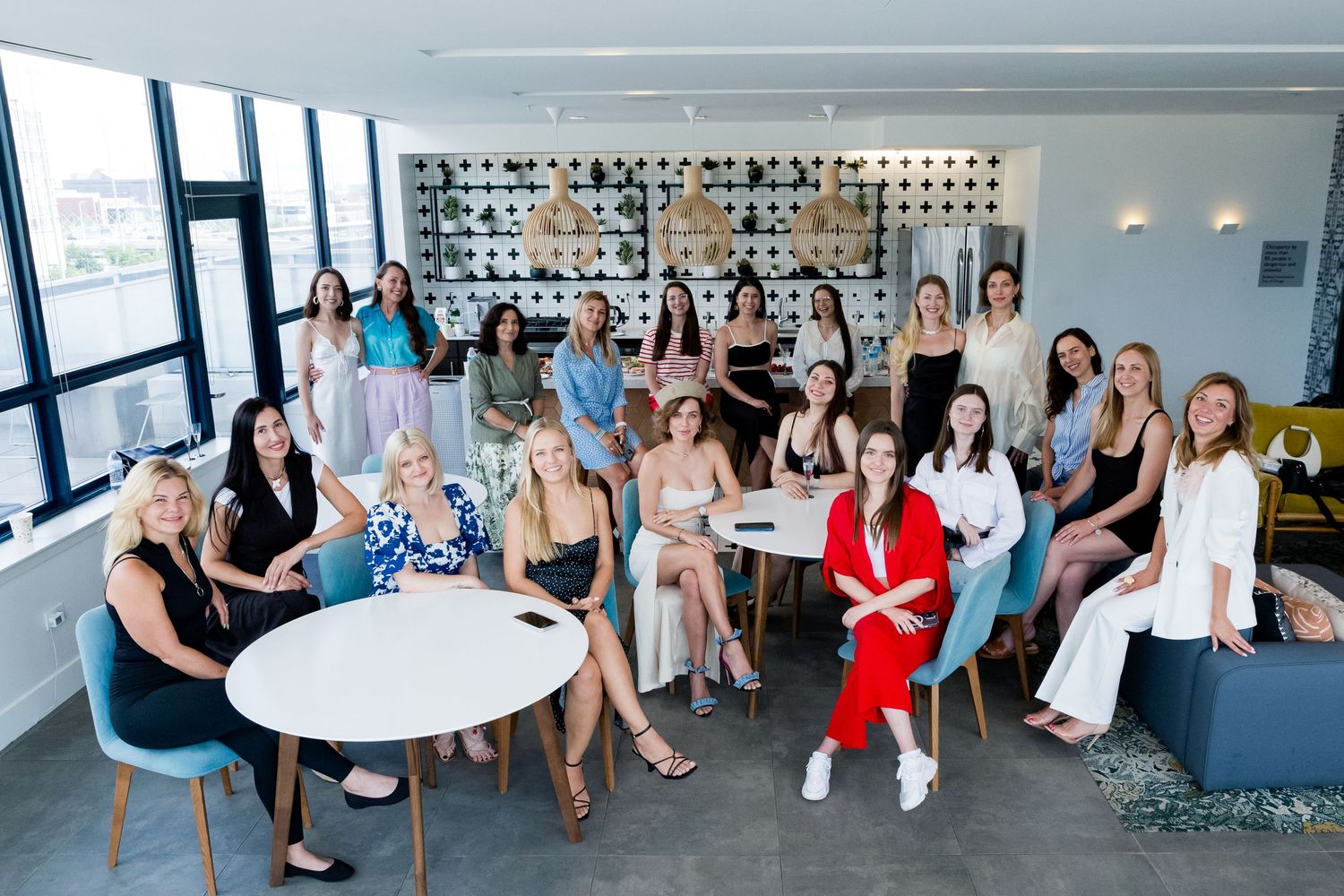 Large group gathered in modern office space with bright windows and contemporary furniture.