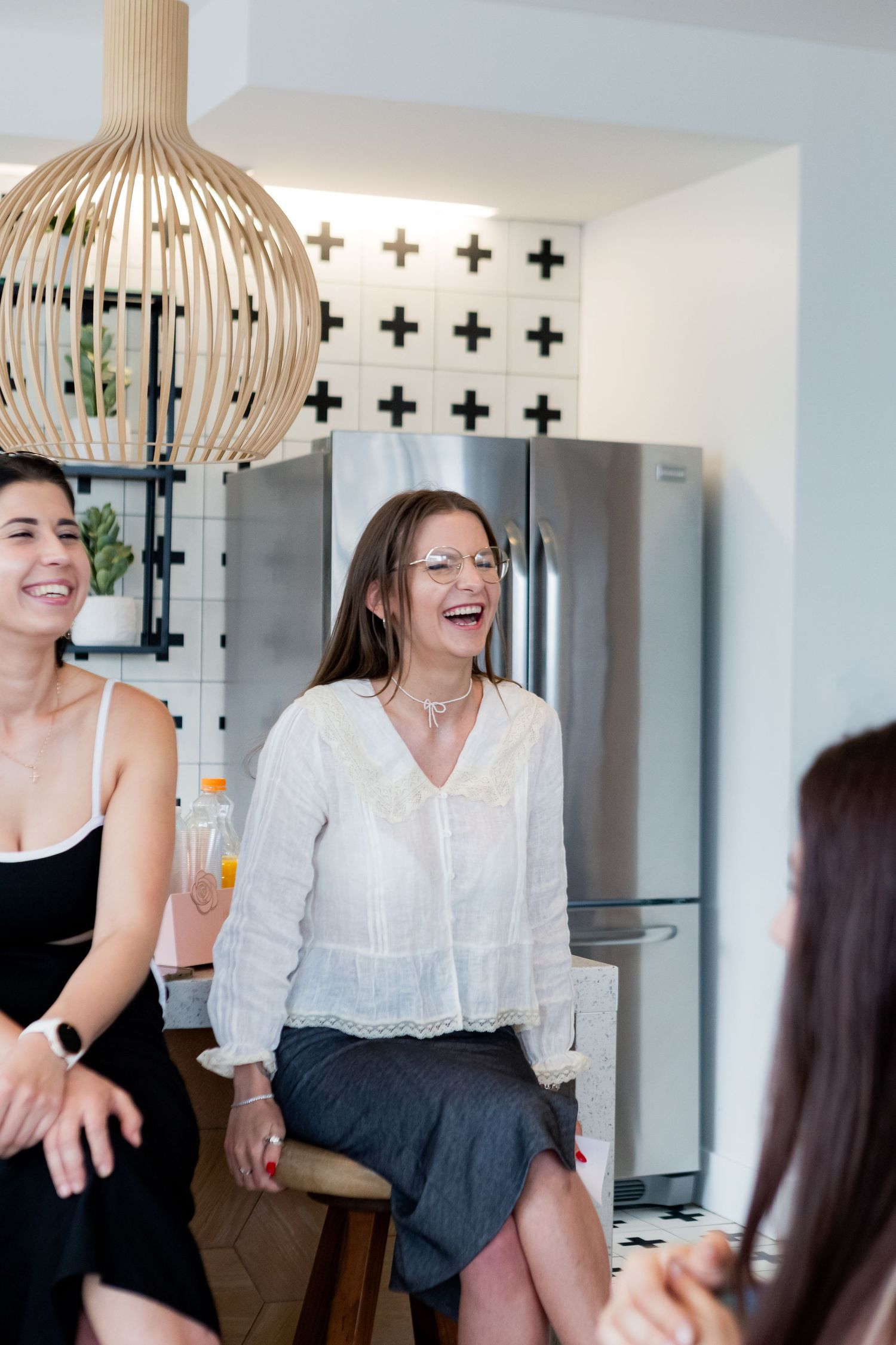 Casual social gathering in modern kitchen with rattan pendant light and cross-pattern wall.