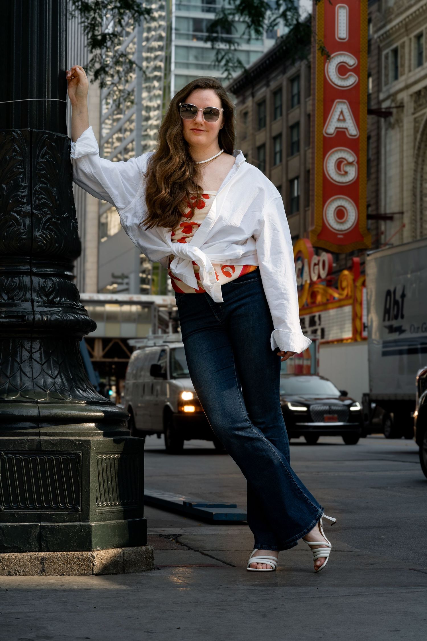 Urban fashion photo in front of Chicago Theater sign wearing casual white and orange outfit.