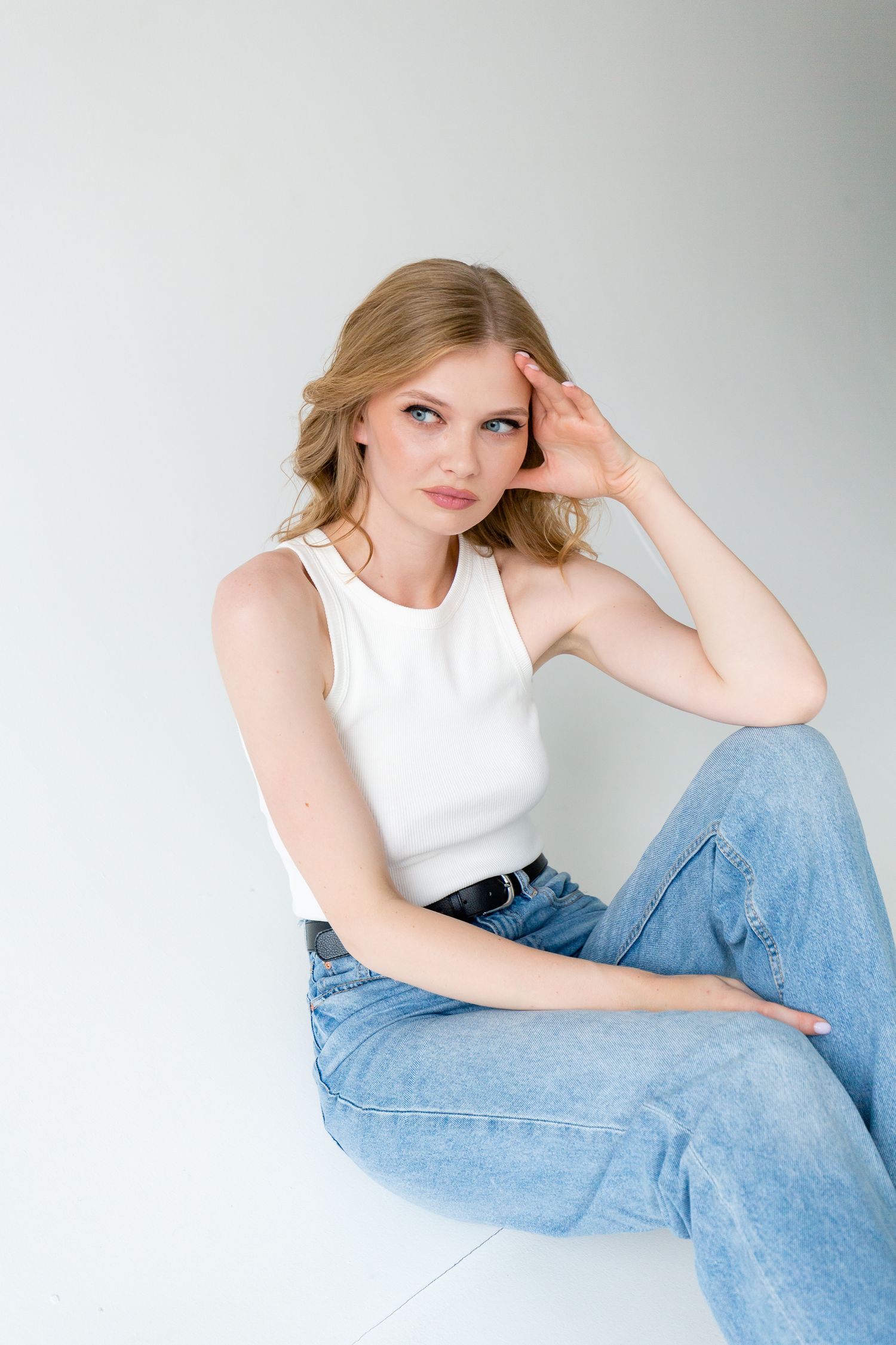 Fashion portrait featuring casual styling with white tank top and classic blue denim.