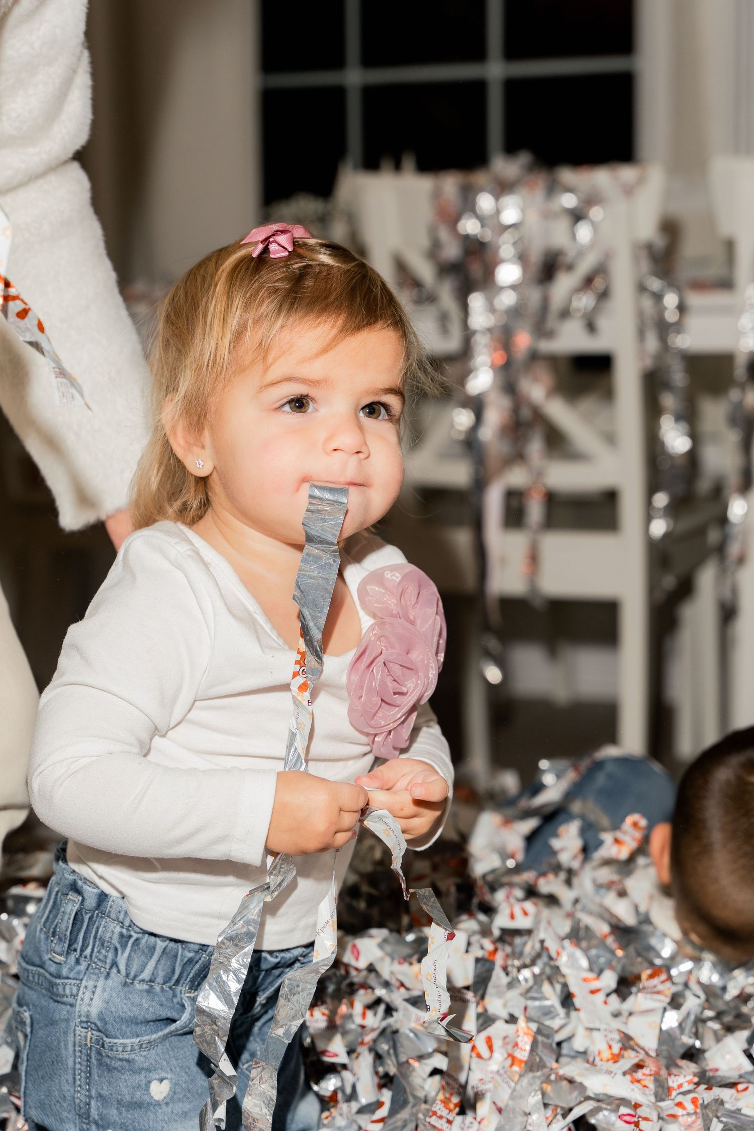 Small child in white sweater playing with streamers during a party celebration.
