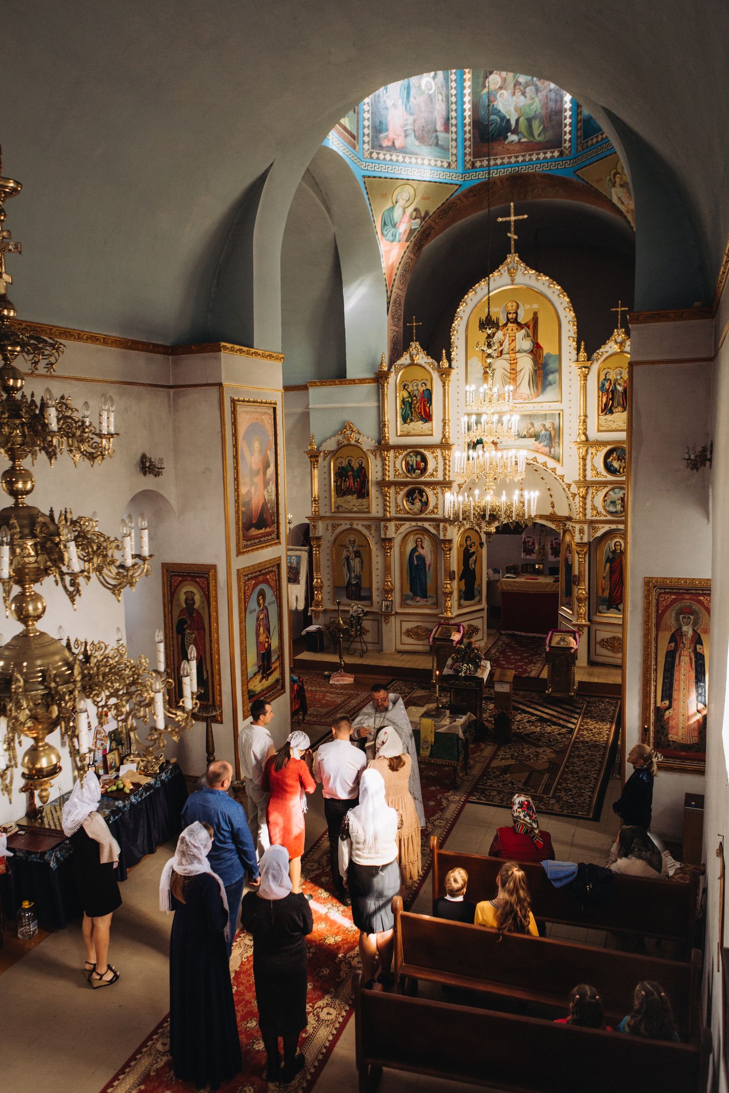 Aerial view of Orthodox church interior showing ornate iconostasis and gathered congregation.