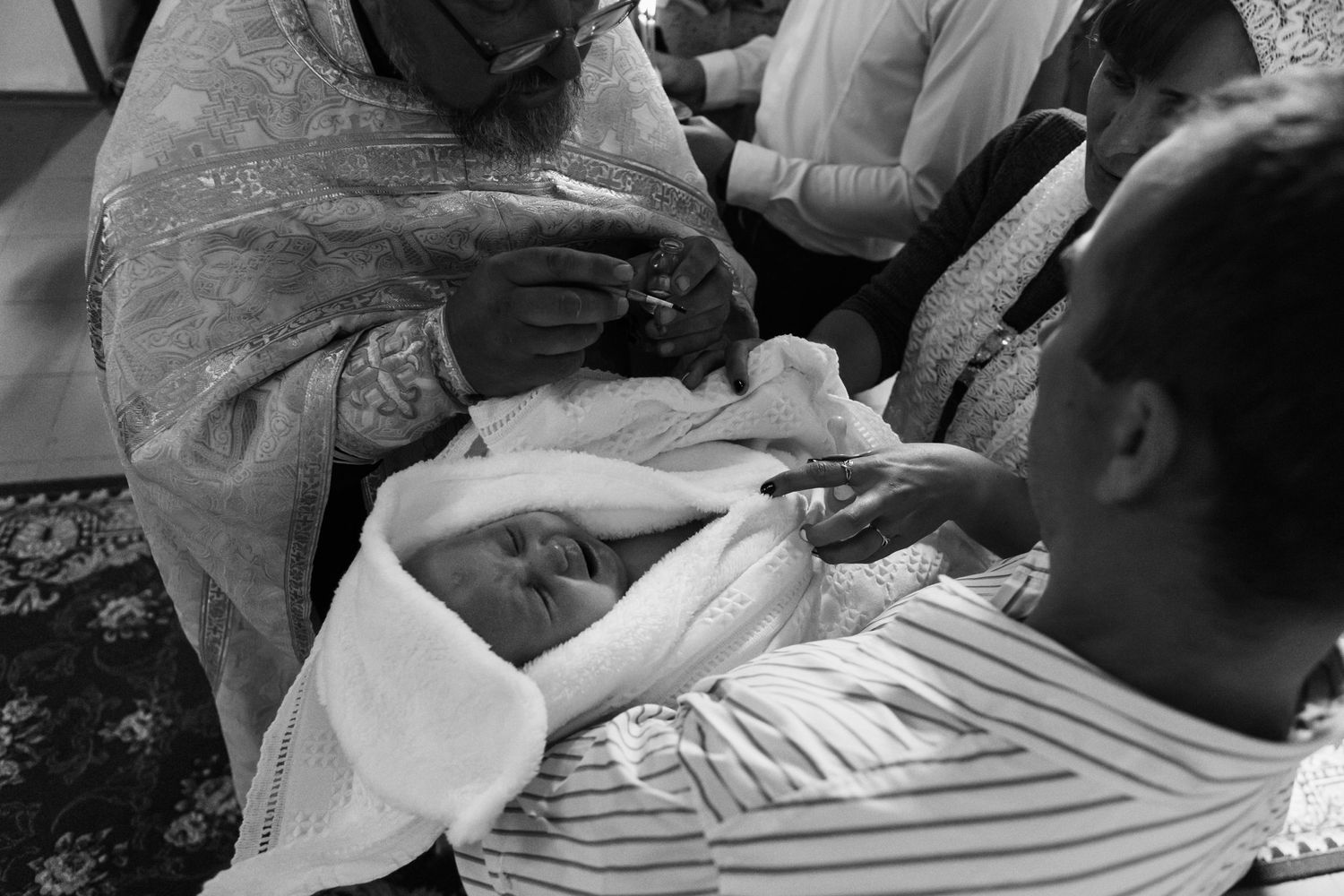 Black and white photo of religious ceremony showing priest performing ritual.
