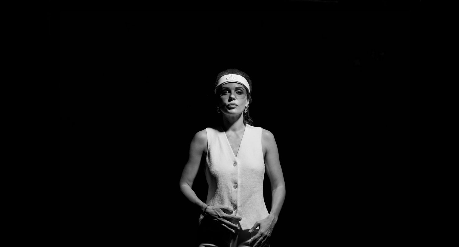 Dramatic black and white portrait of a figure in athletic wear against dark background.