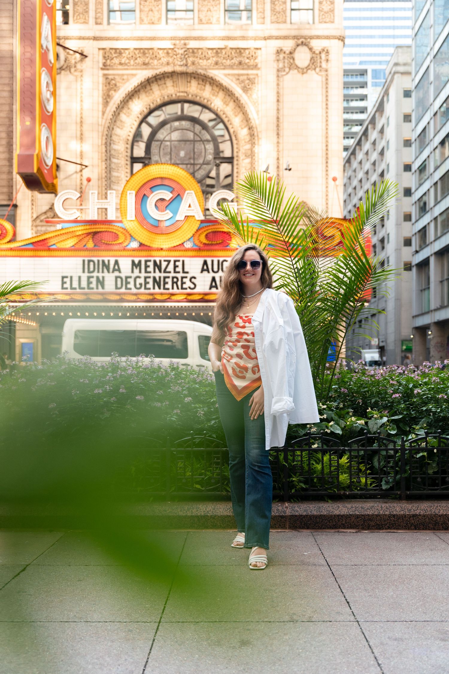 Fashion portrait in front of Chicago Theater's iconic rainbow sign wearing white button-down shirt.