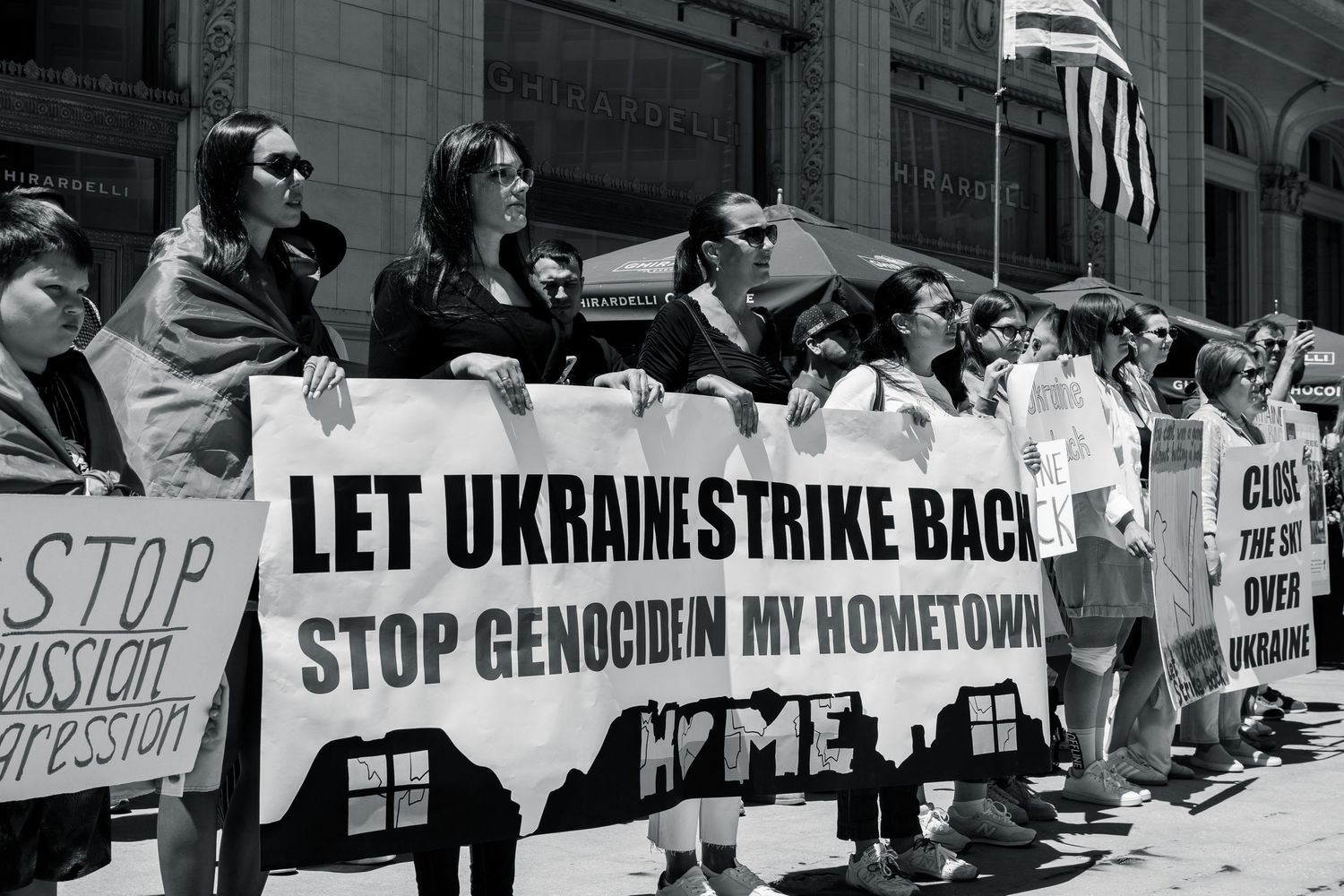 Protesters hold signs supporting Ukraine with Let Ukraine Strike Back message in black and white photo.
