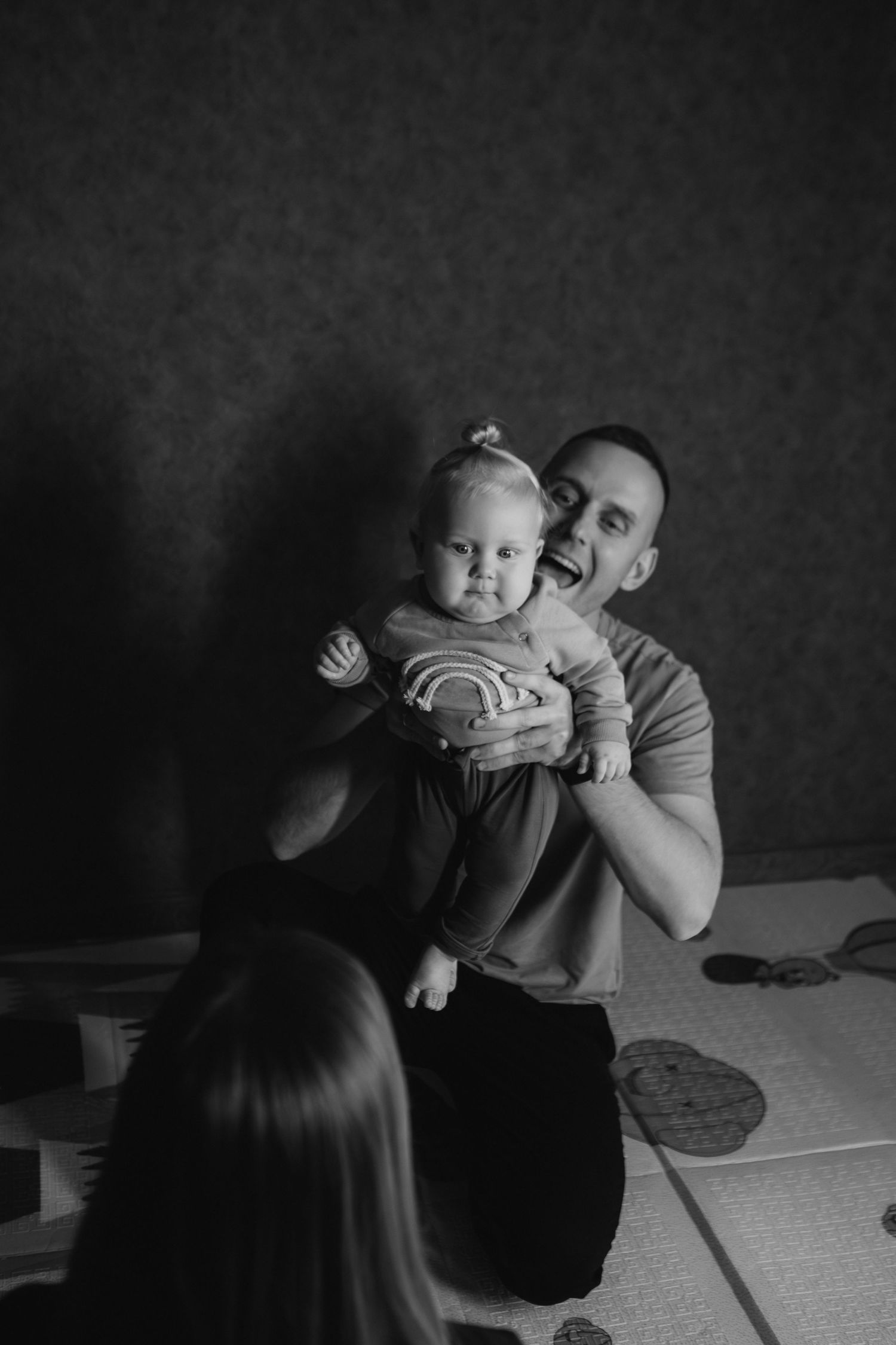 Black and white photo series showing tender moments between a parent and baby in an intimate indoor setting.