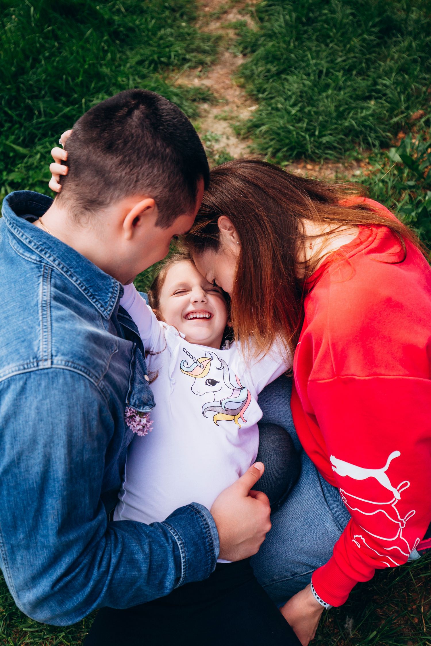 An intimate family moment captured outdoors with joyful expressions and a unicorn t-shirt.