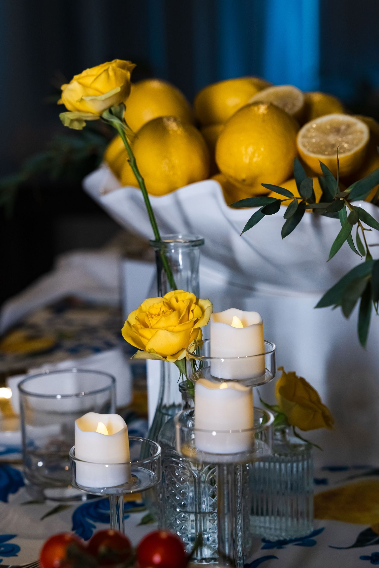 Yellow roses and lemons table setting with white candles creating romantic ambiance.
