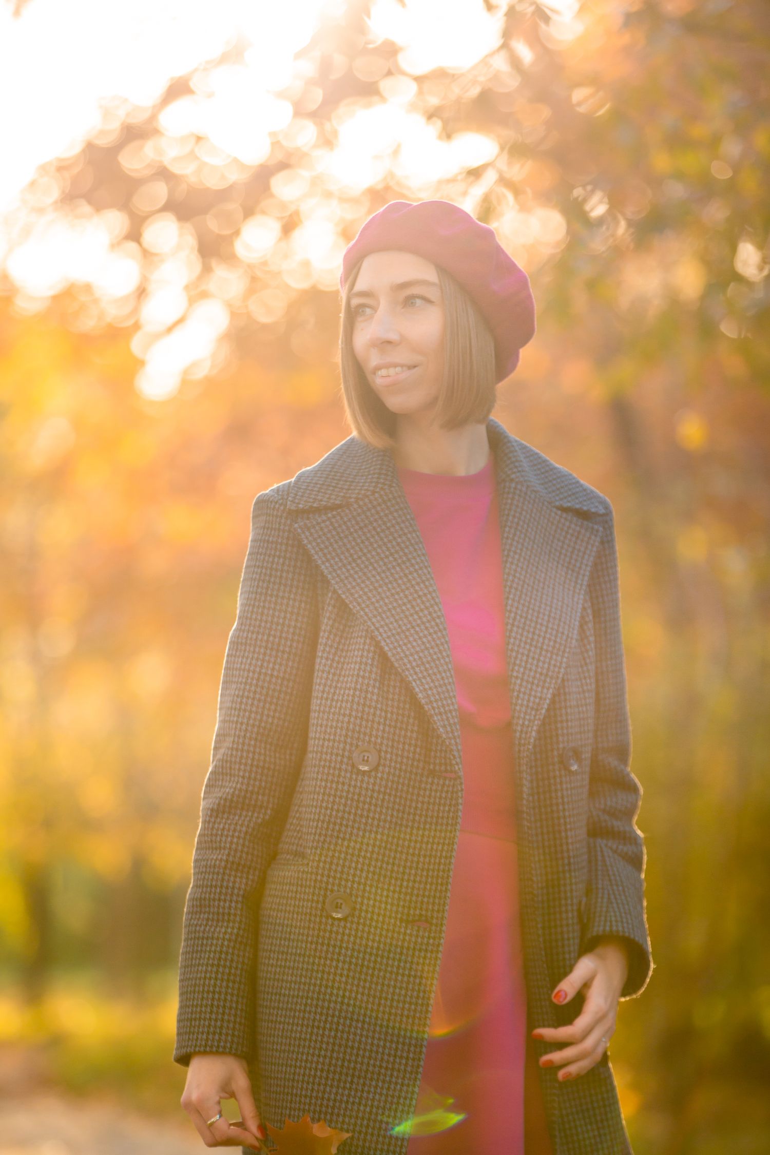 Atmospheric golden hour portrait featuring checked coat and burgundy beret against autumn light.