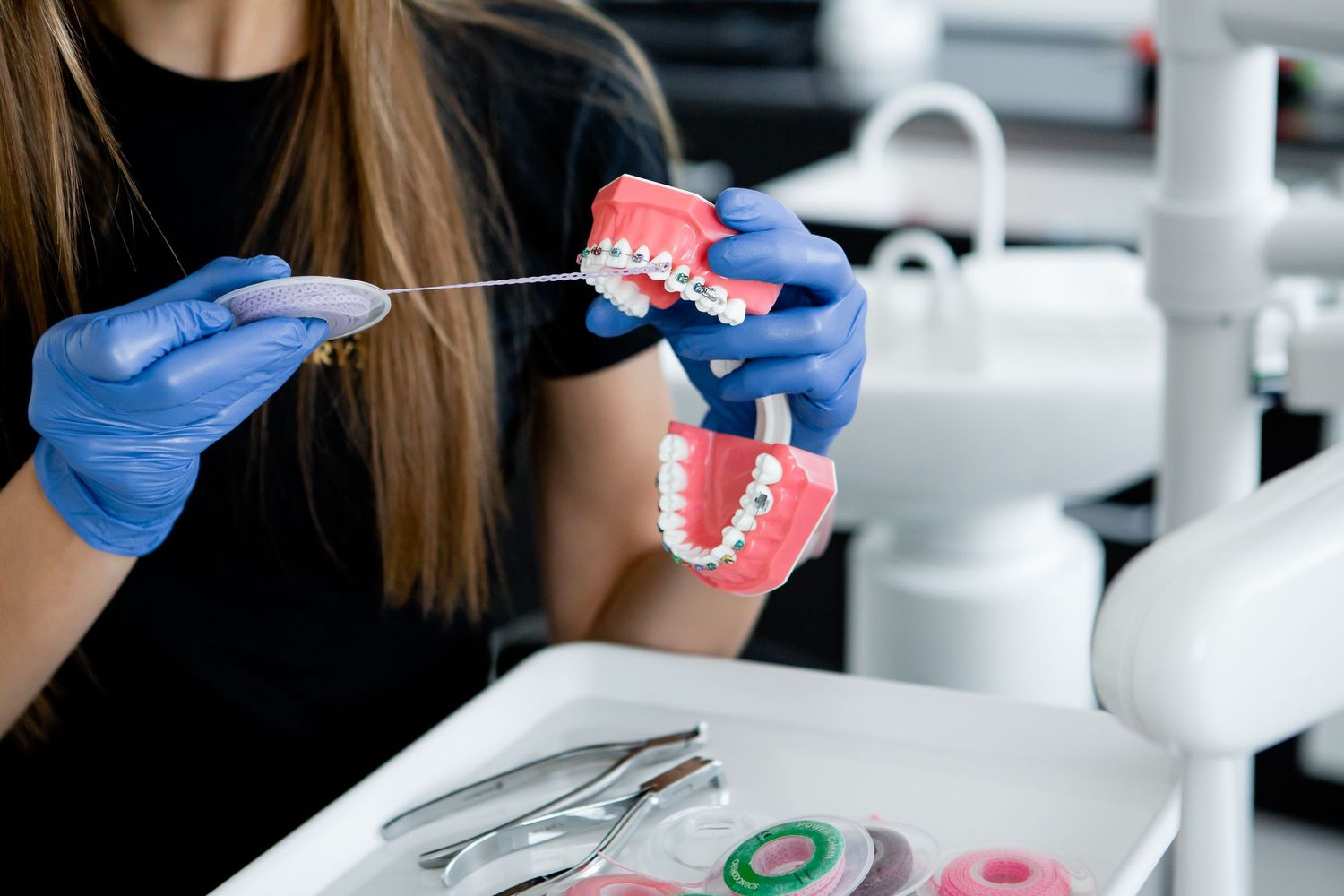 Hands in blue gloves demonstrating proper dental care using educational model.