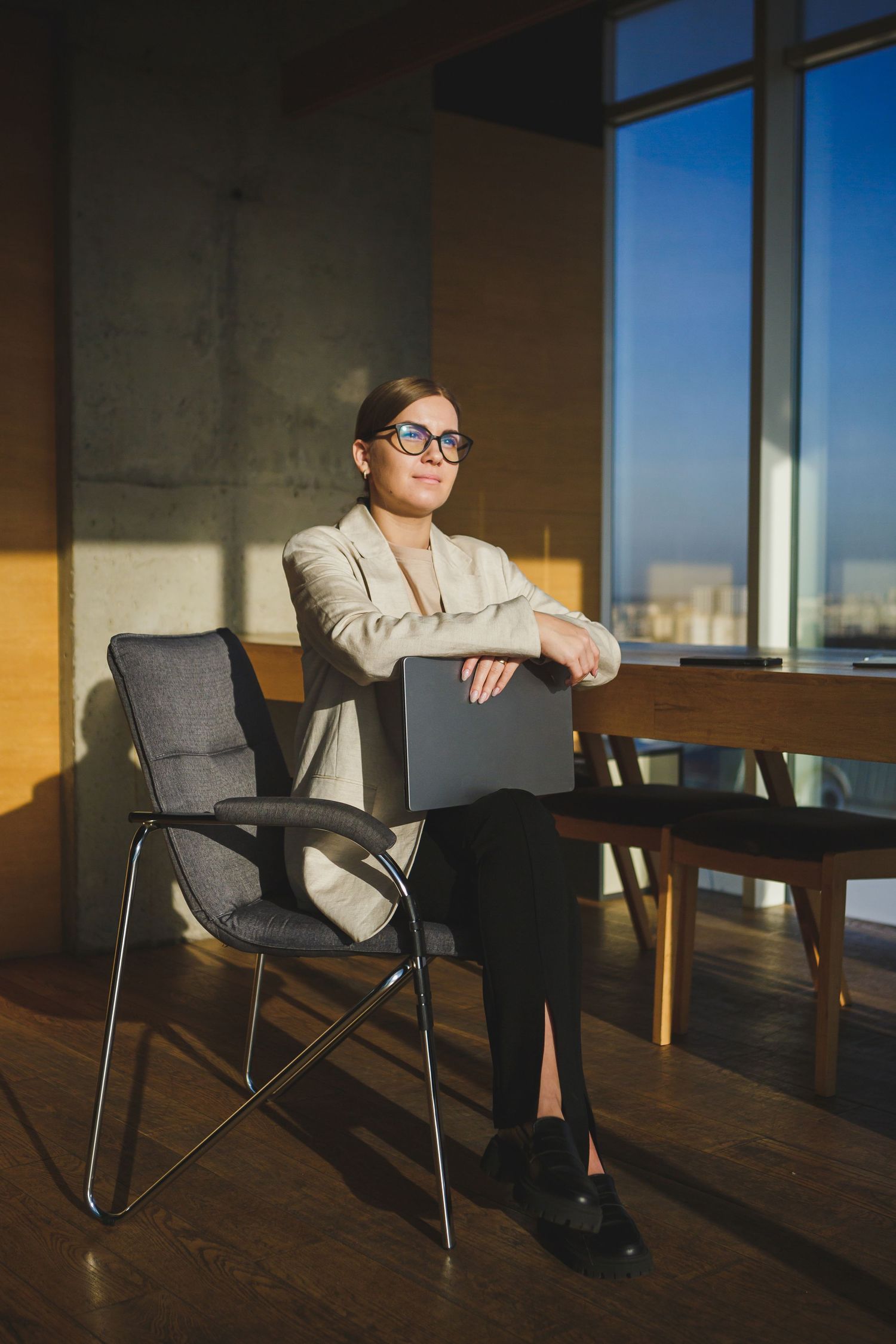 Business person in light blazer sitting with folder in modern office space.
