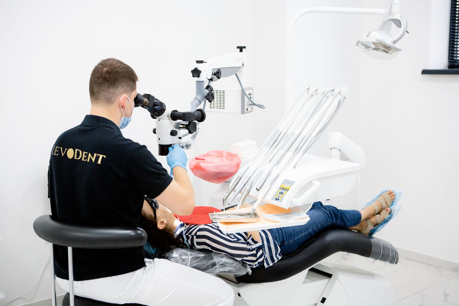 Dental professional using microscope equipment during patient treatment.
