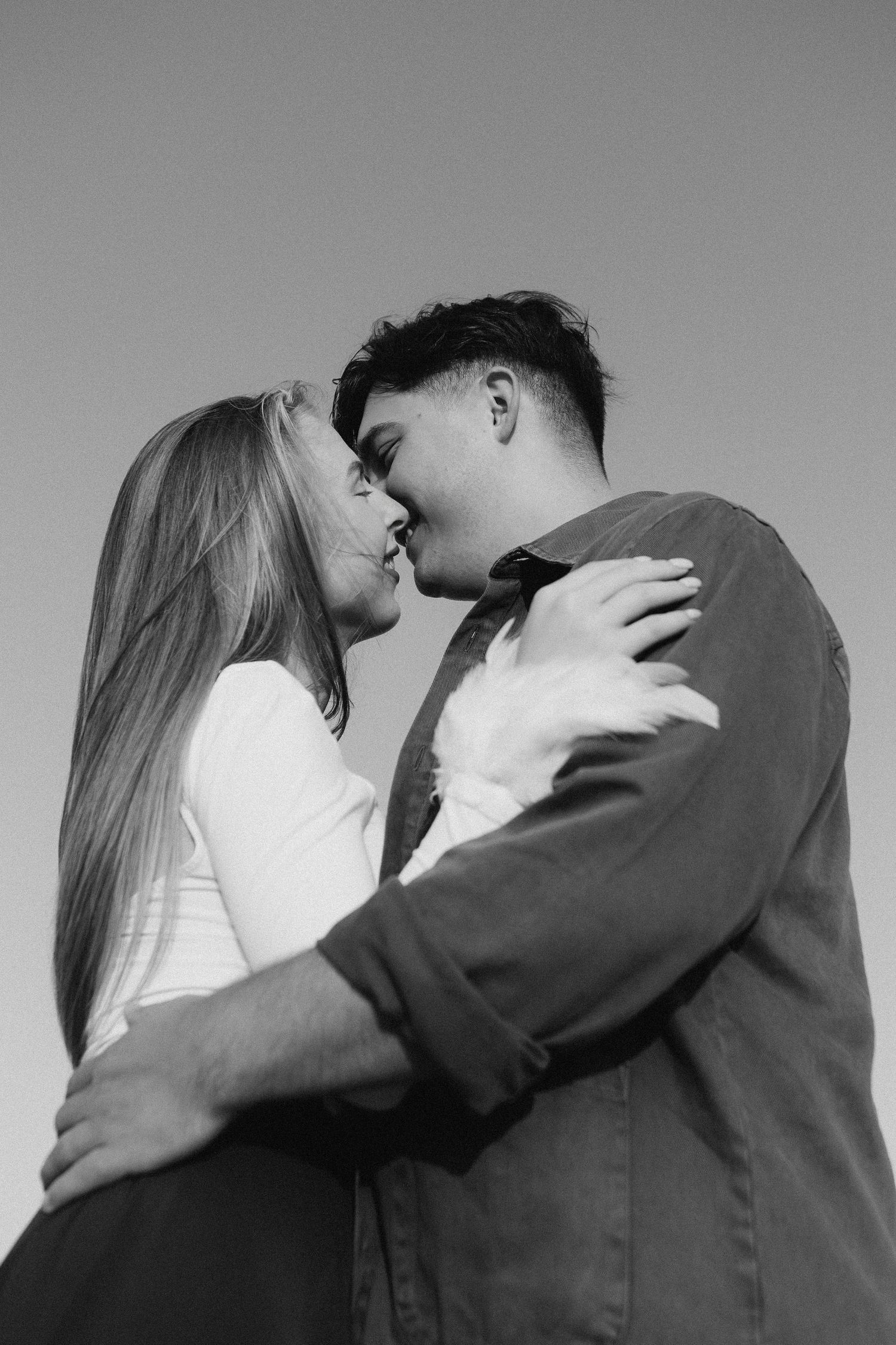 A series of black and white romantic photos showing a couple embracing and kissing against a plain background.