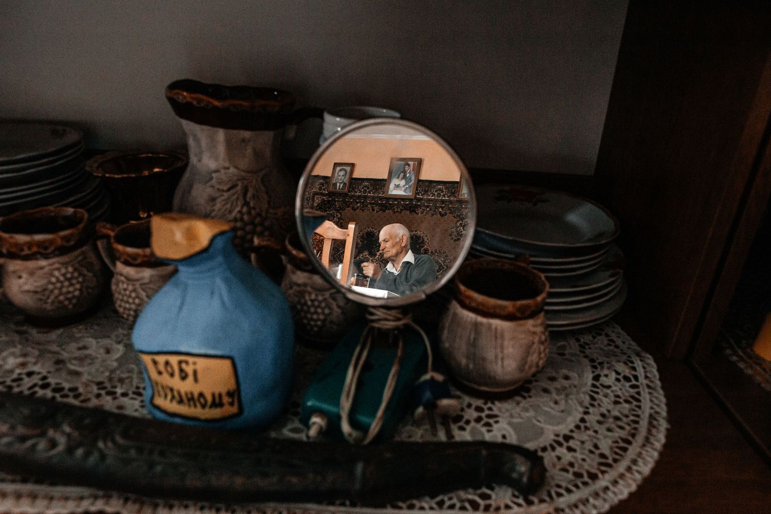 Vintage dishware and a reflective mirror arranged on a countertop with intricate lace doily.