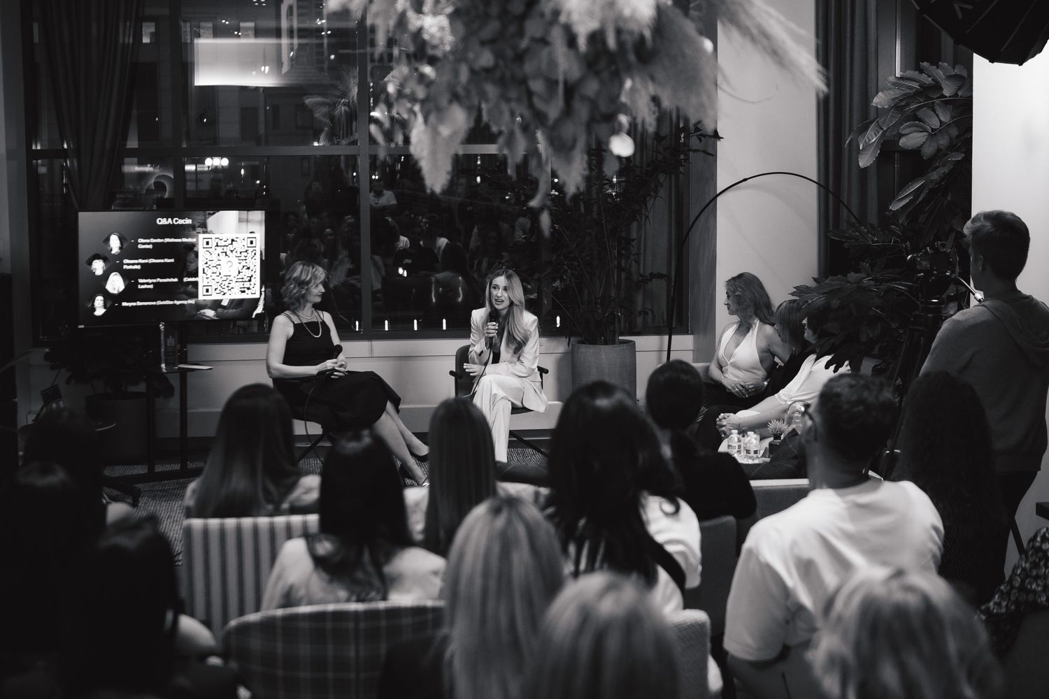 Black and white photo of an audience watching a business presentation in a modern space.