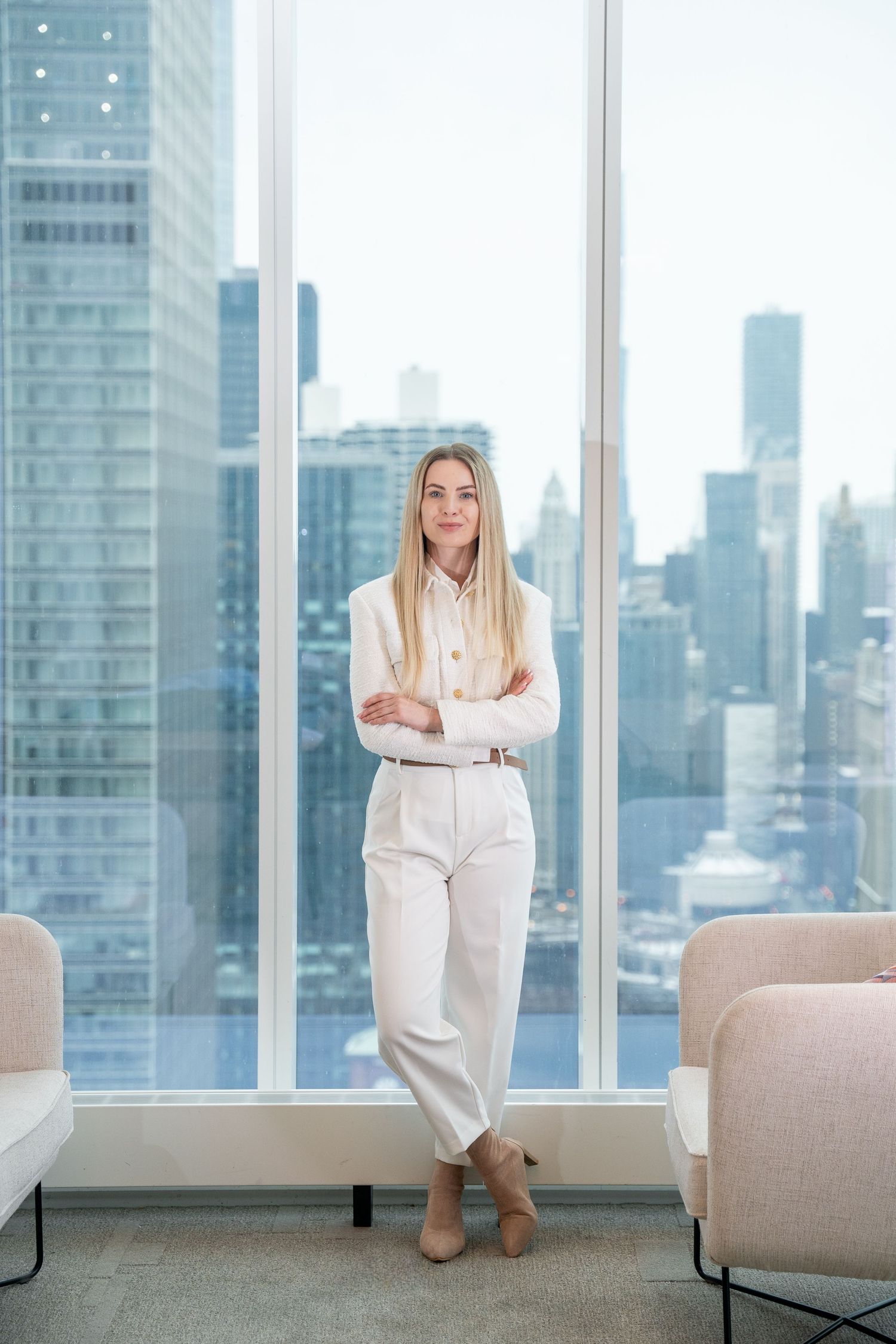 Professional in white outfit poses against city skyline backdrop.