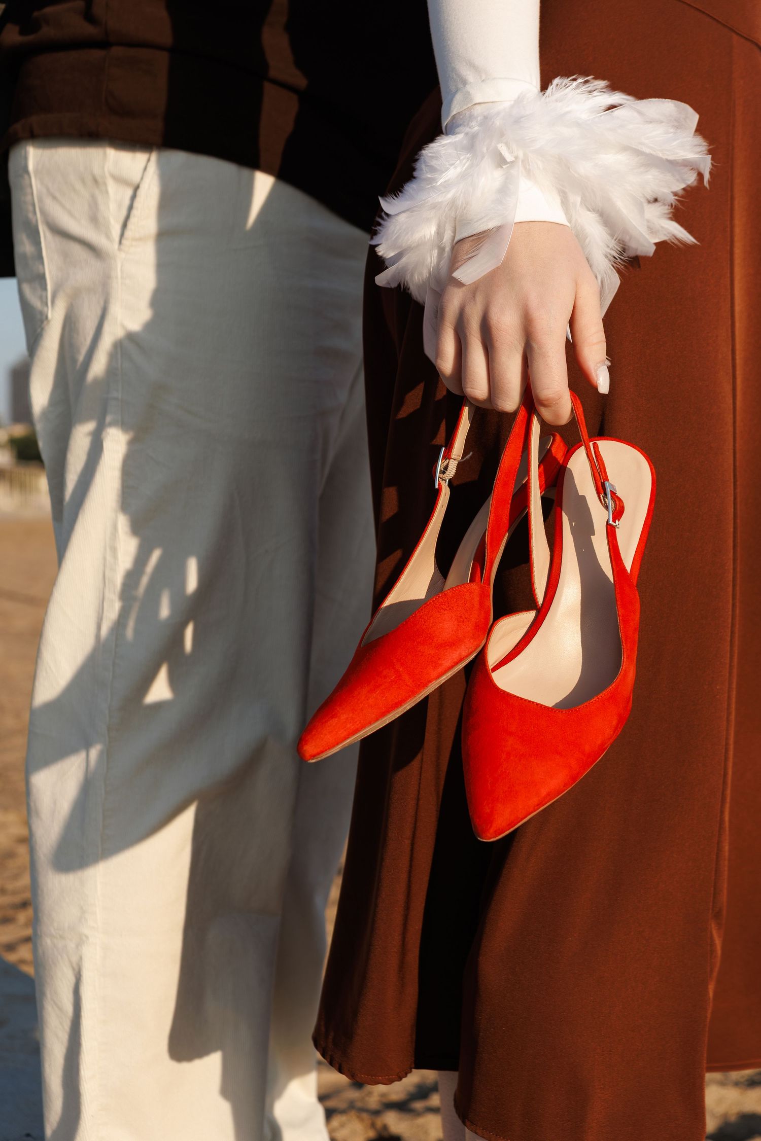 A series of images showing hands holding bright red high heel shoes against a brown and beige background.