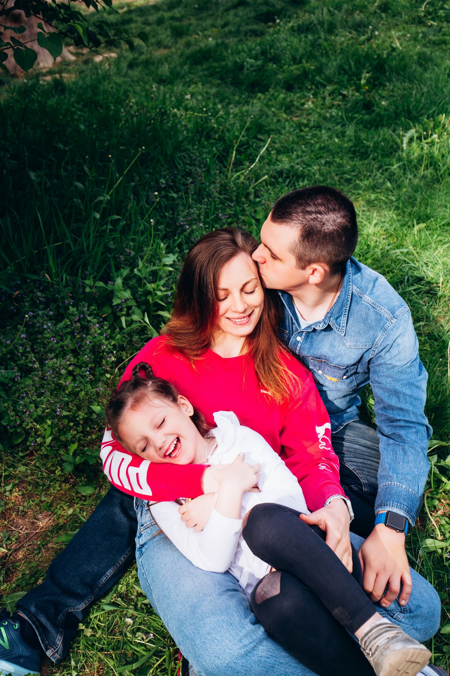 A joyful family moment captured on the grass during a sunny spring day.