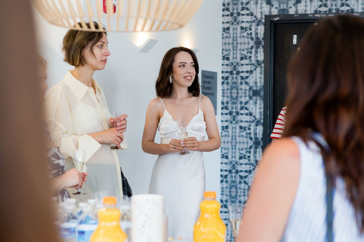 Women enjoying conversation at bright modern party space with geometric light fixture.