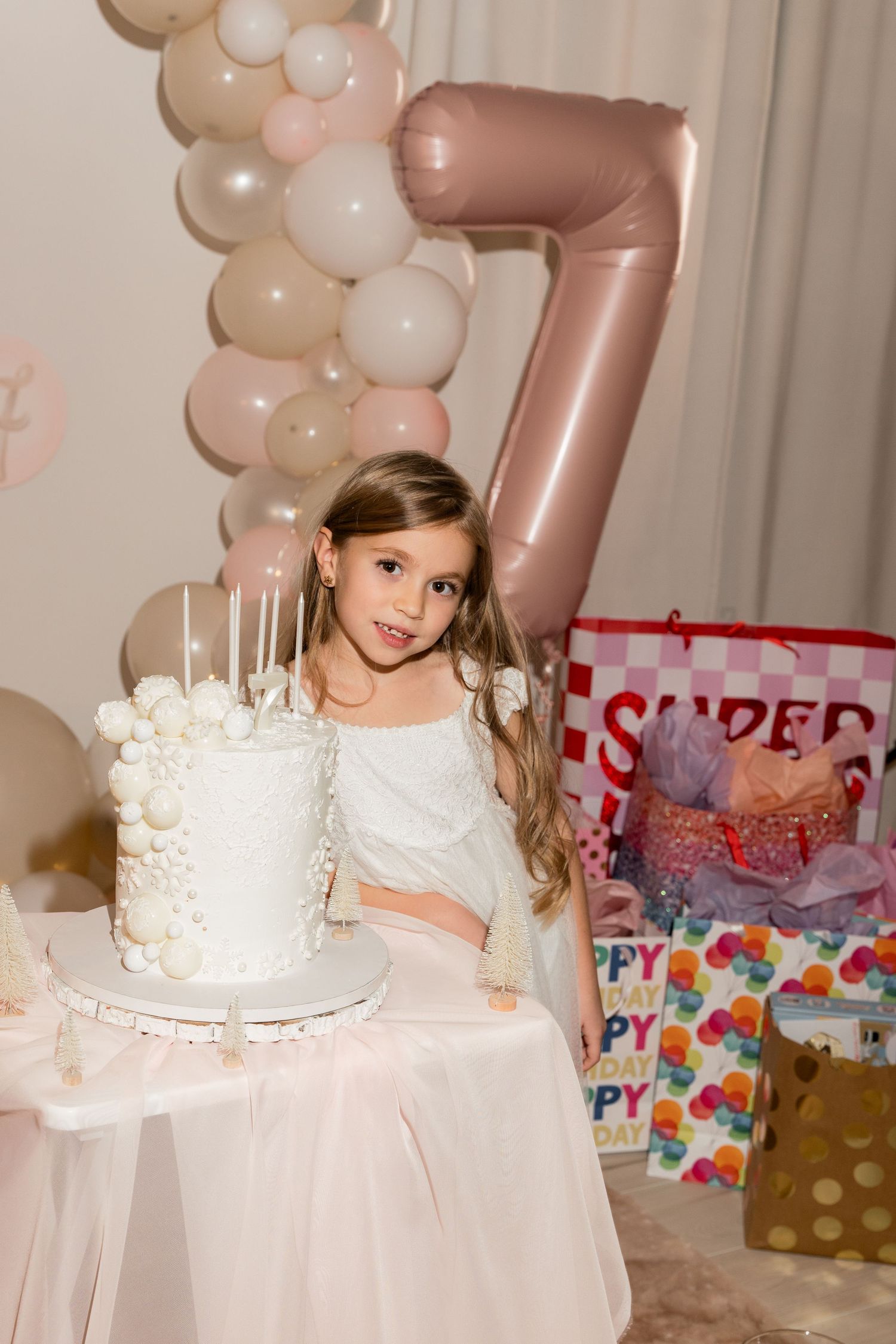 Birthday celebration with white cake and rose gold number 7 balloon decoration.