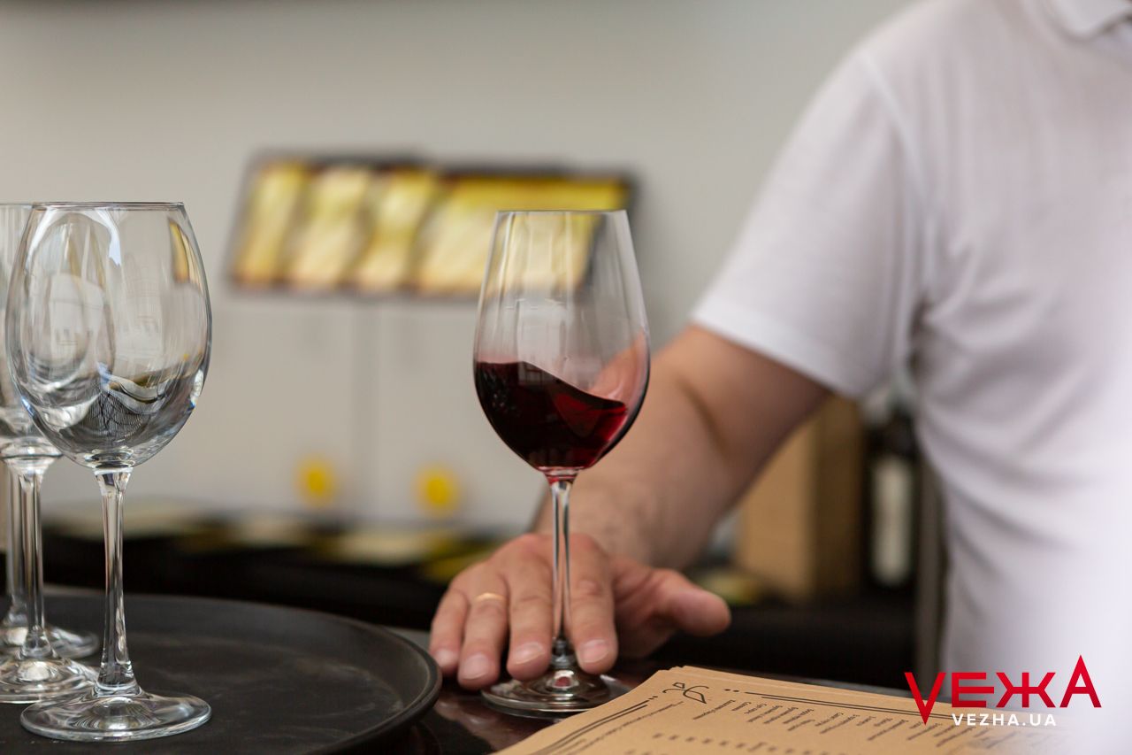 Wine glasses arranged on dark surface with single glass of red wine.