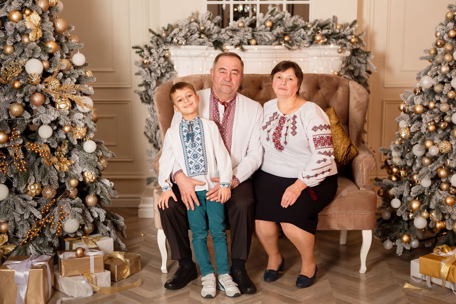 Family group in traditional embroidered attire poses between decorated Christmas trees.