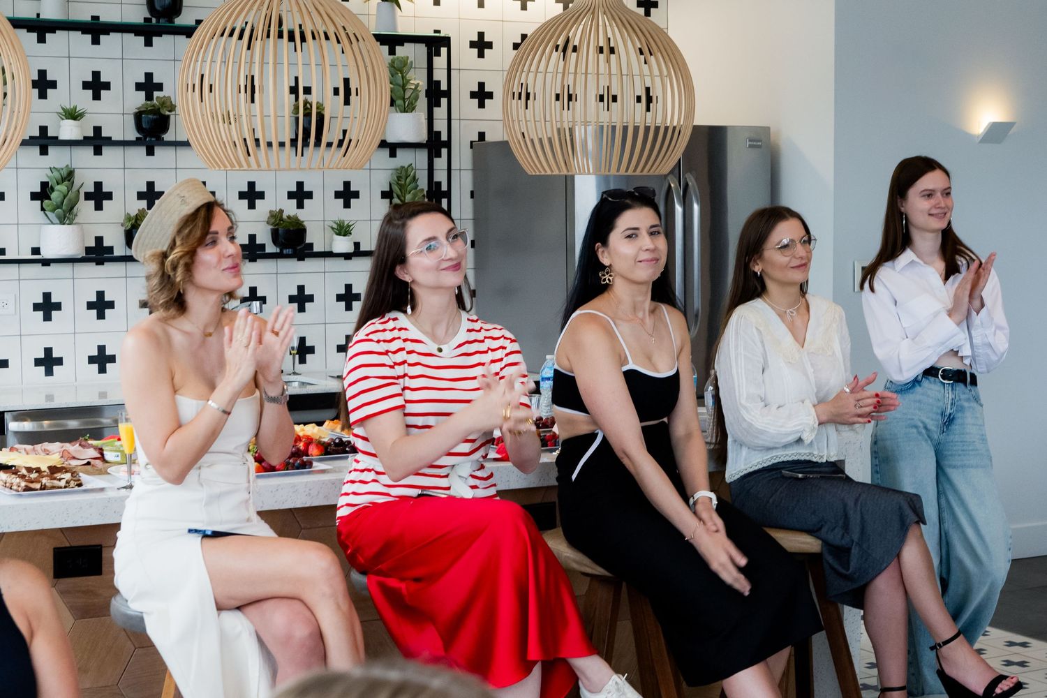 Group seated together in modern space with pendant lighting and patterned wall design.