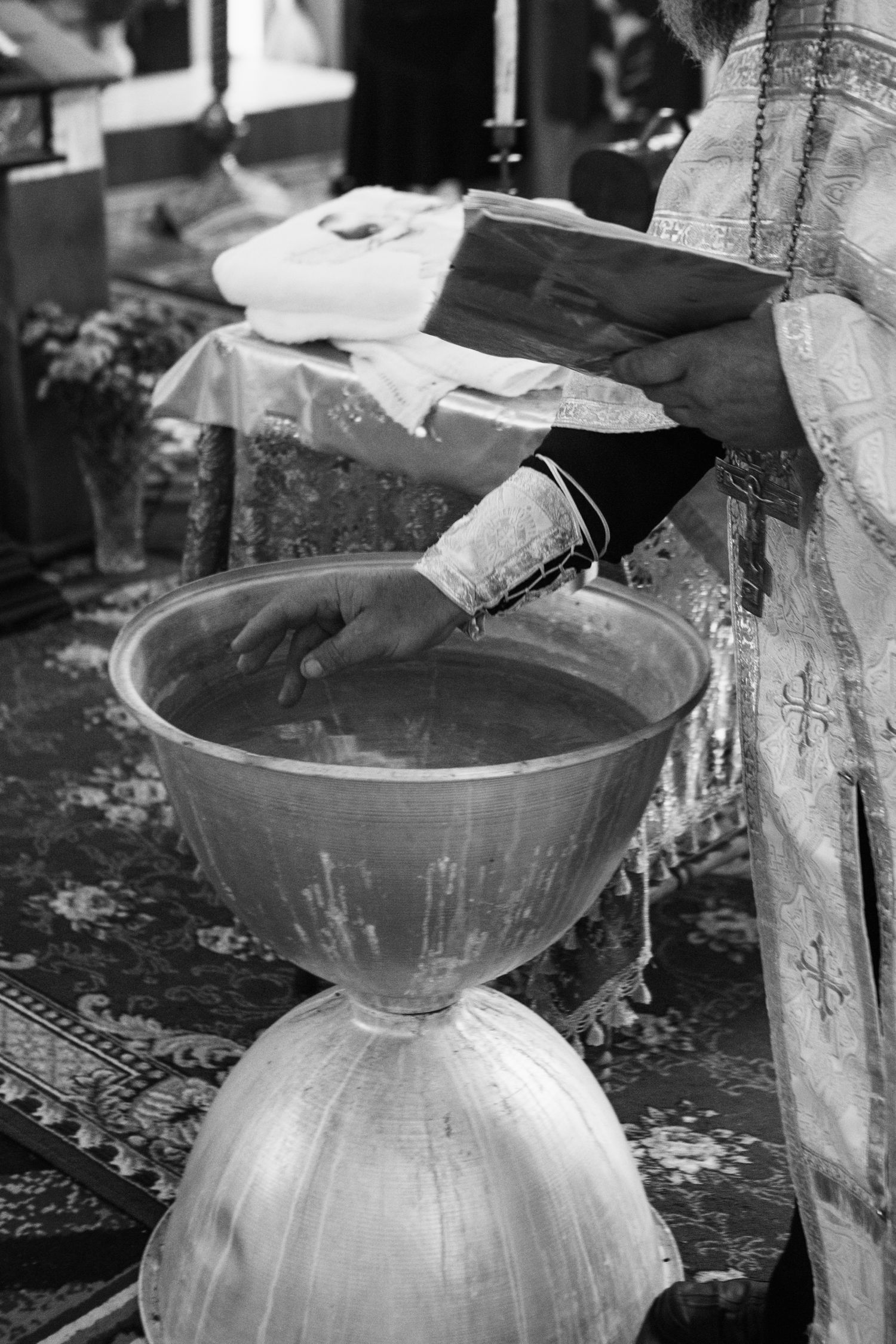 Black and white photo of holy water being blessed during an orthodox christian baptism ceremony.