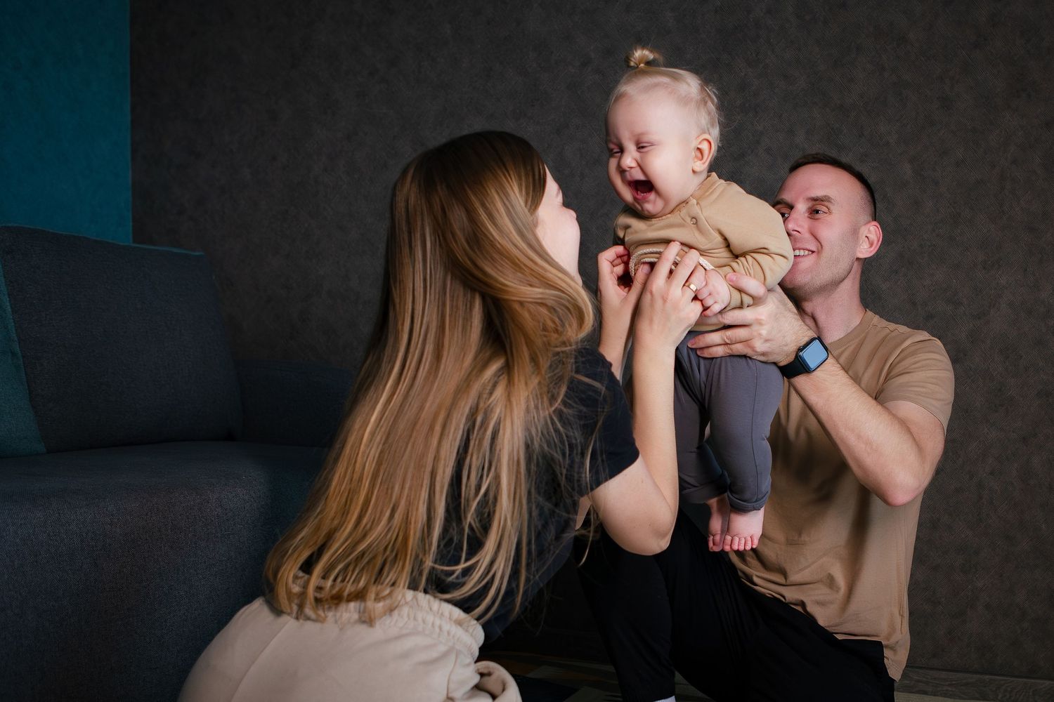 A series of intimate family portrait photos showing tender moments between parents and their baby against a dark background.