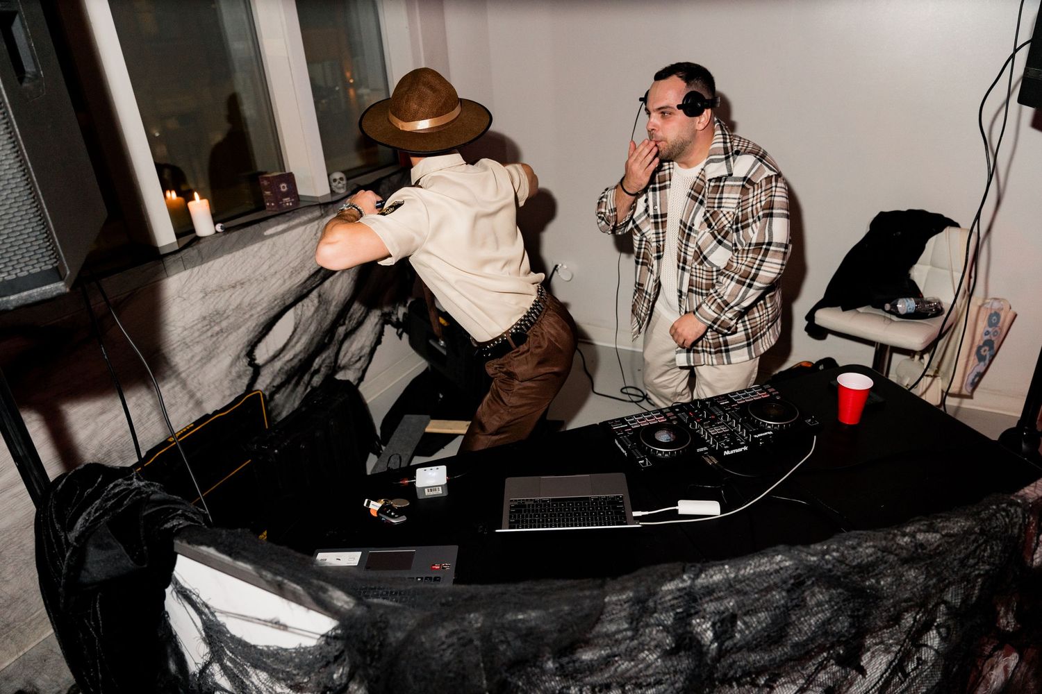 Two people in costumes pose on a mechanical bull at a party.