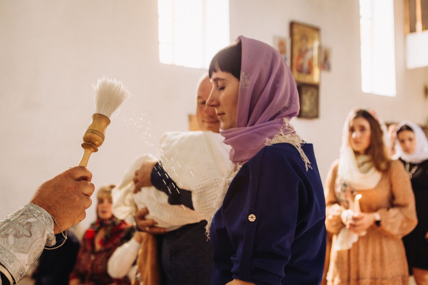 Religious ceremony with holy water aspergillum in Orthodox church setting.