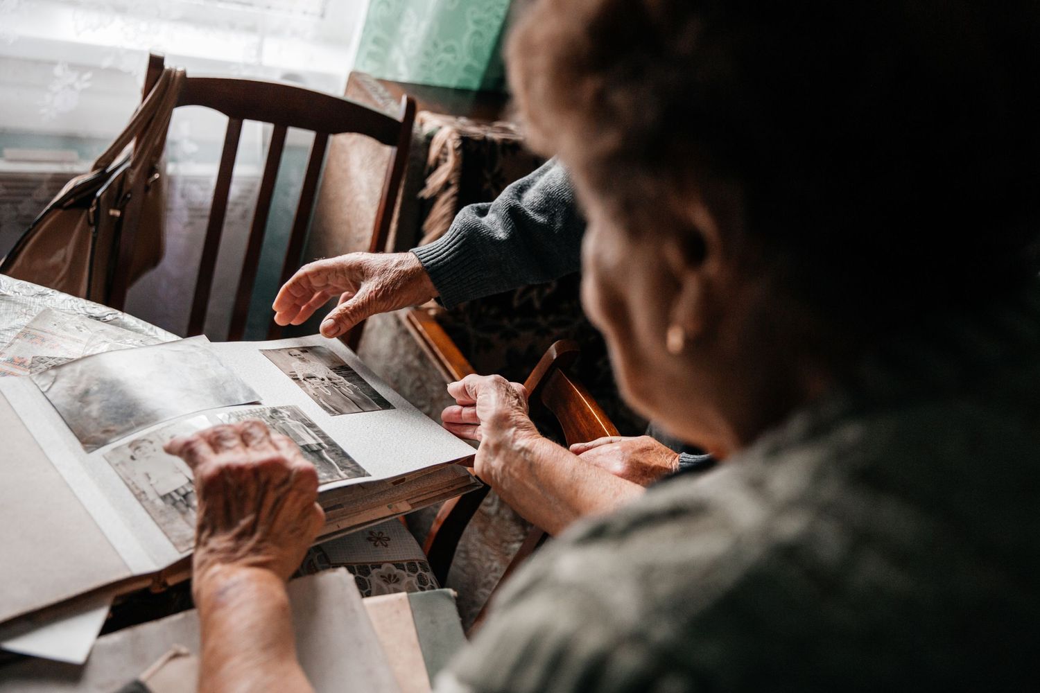 Person looking through documents at a wooden table in natural light.