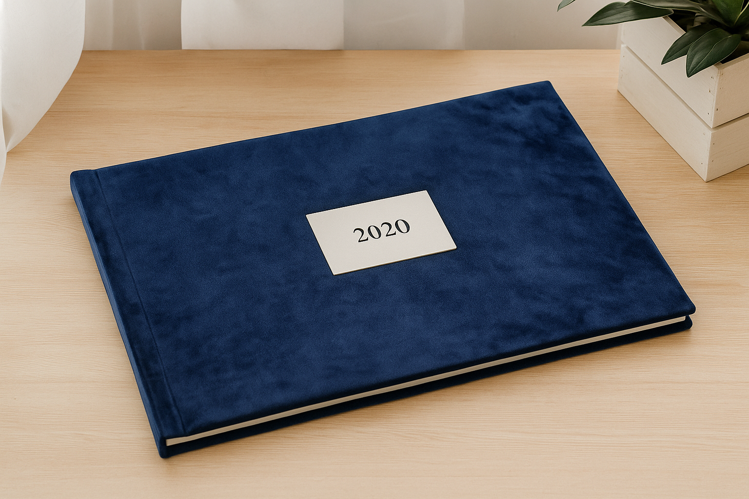A navy blue velvet photo album or scrapbook with '2020' label on wooden surface next to decorative items.