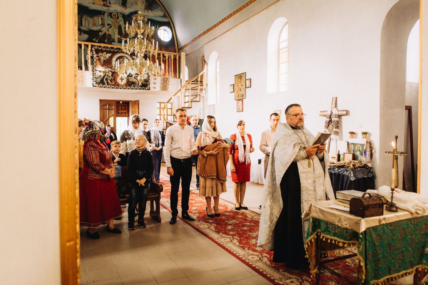Orthodox Christian priest performs religious ceremony in traditional church with congregation gathered.