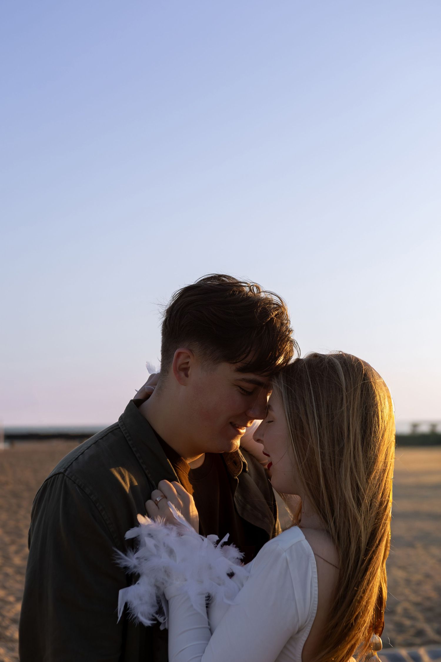 A couple shares an intimate moment at sunset in a field as vape smoke swirls around them.