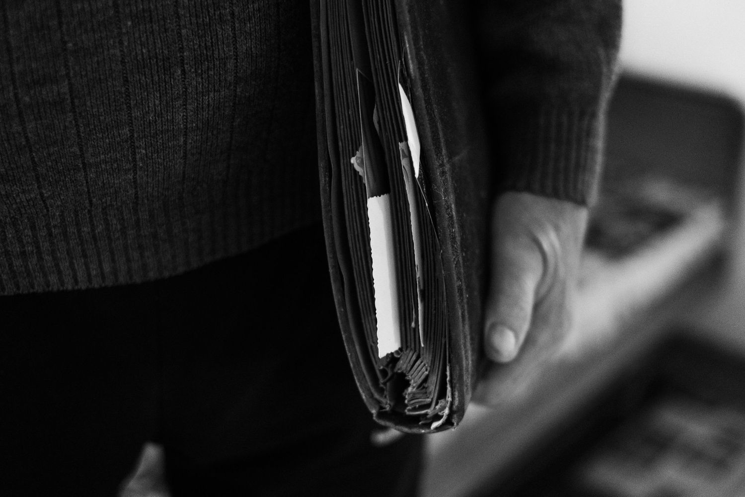 Close-up black and white shot of hands holding a small book or wallet.