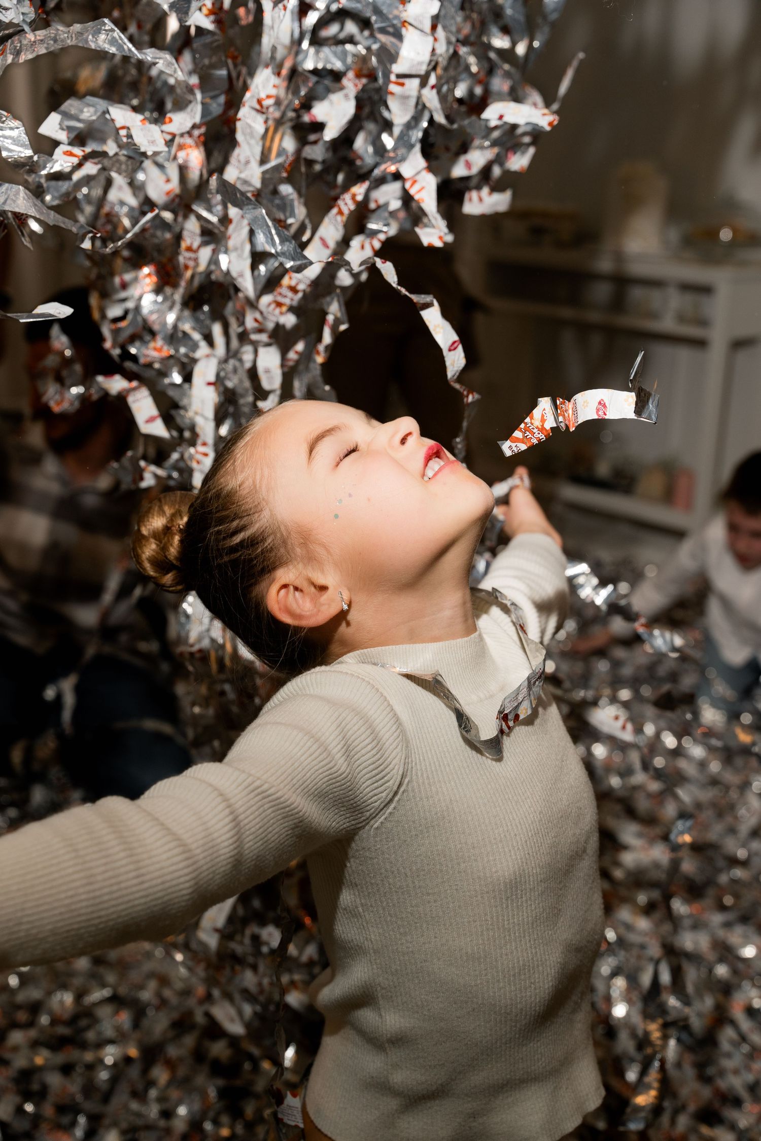 Joyful celebration moment with silver confetti falling around person in gray sweater.