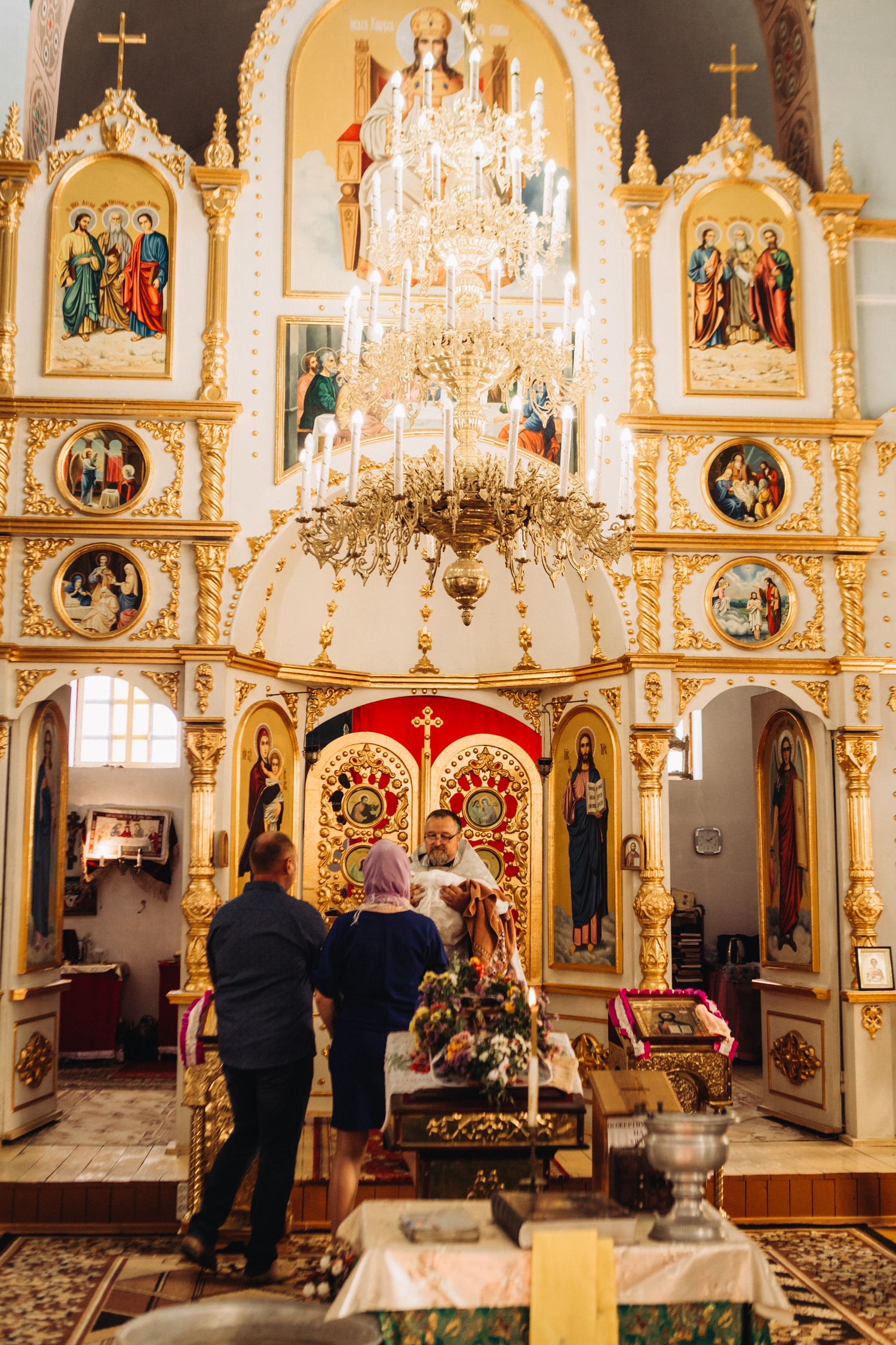 Ornate Orthodox church interior with golden iconostasis and chandelier.