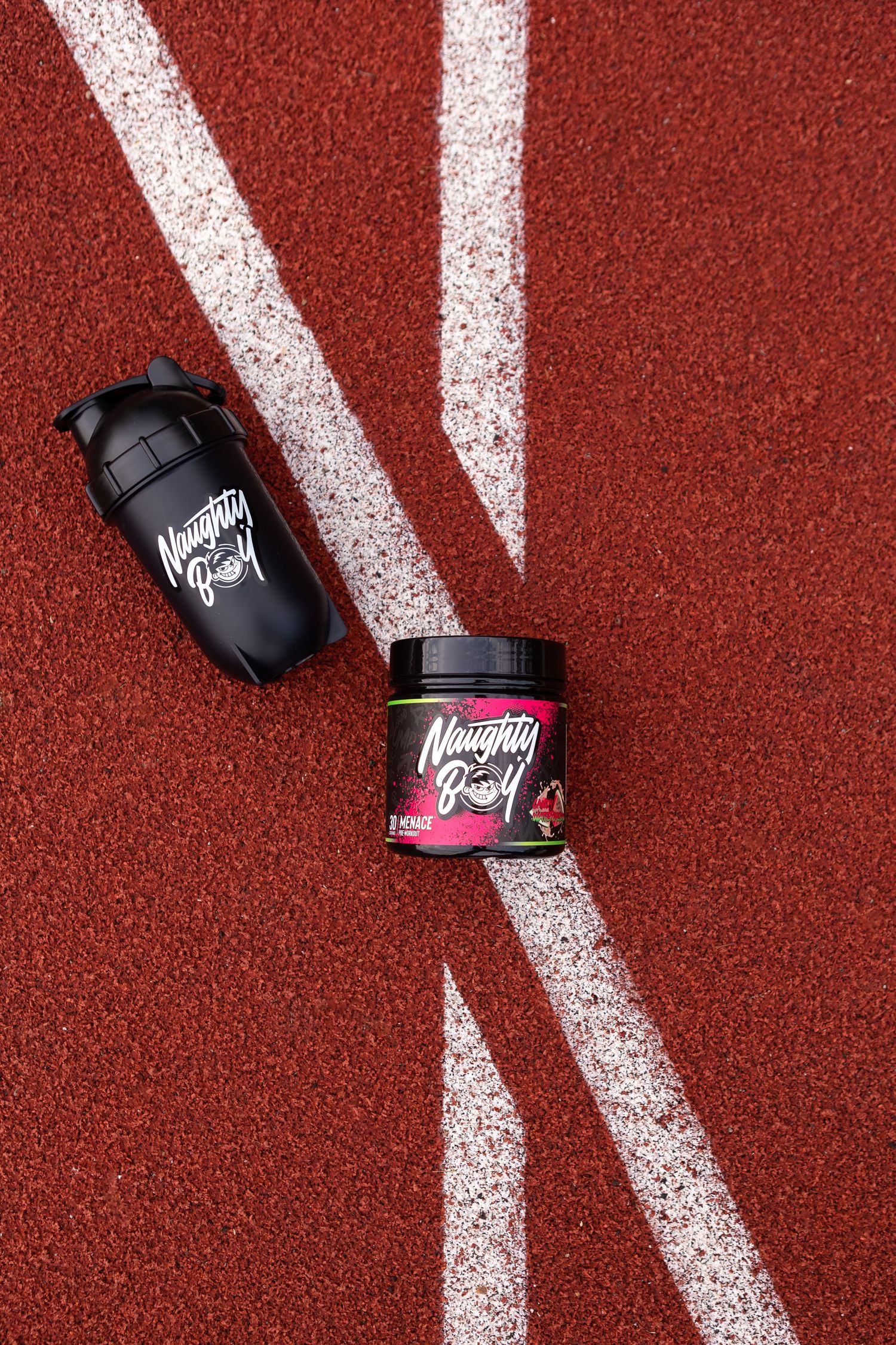 Two black Mountain Dew bottles arranged on a red running track with white lines.