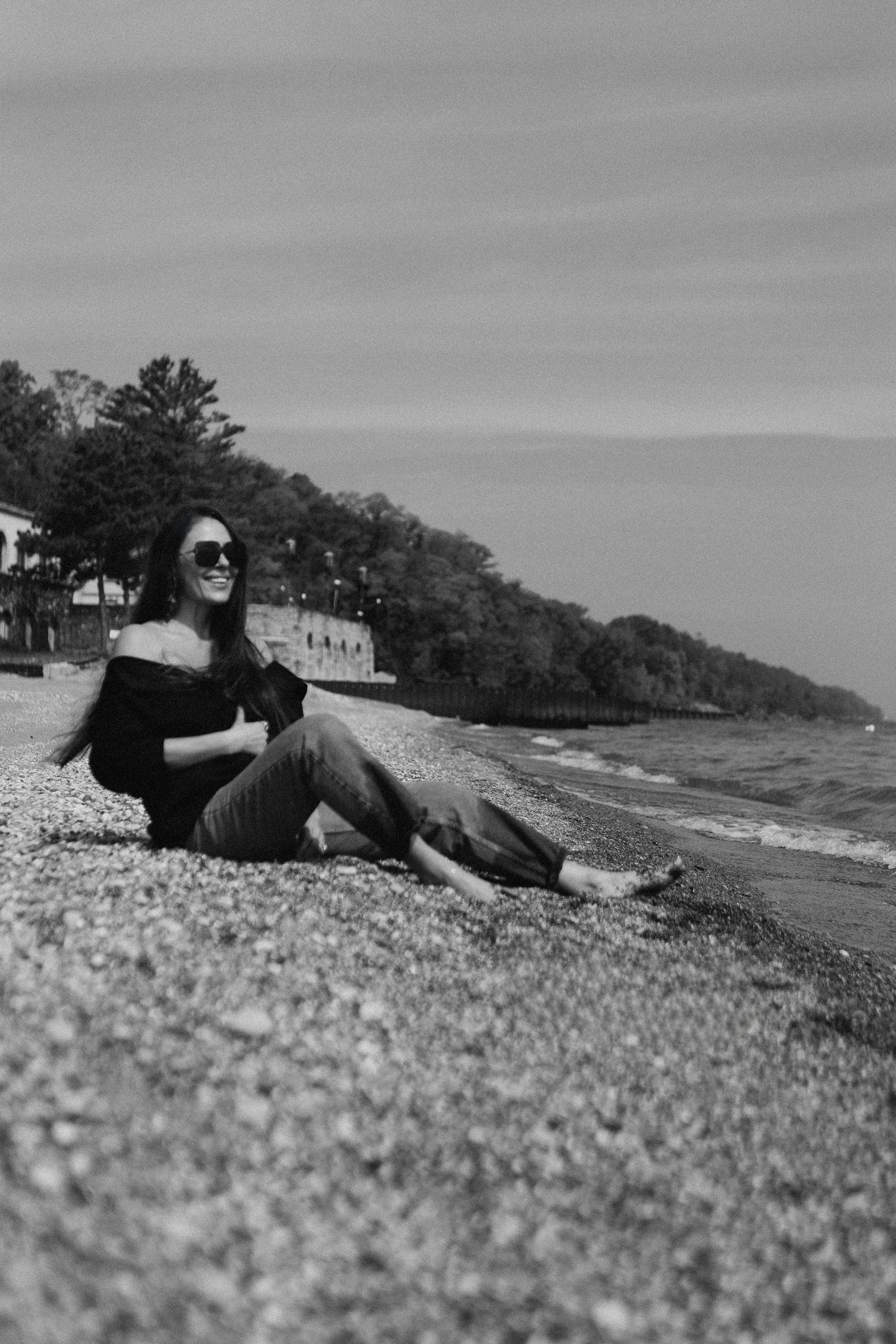 A stylish figure in sunglasses lies on a beach with the ocean and trees visible in multiple black and white frames.