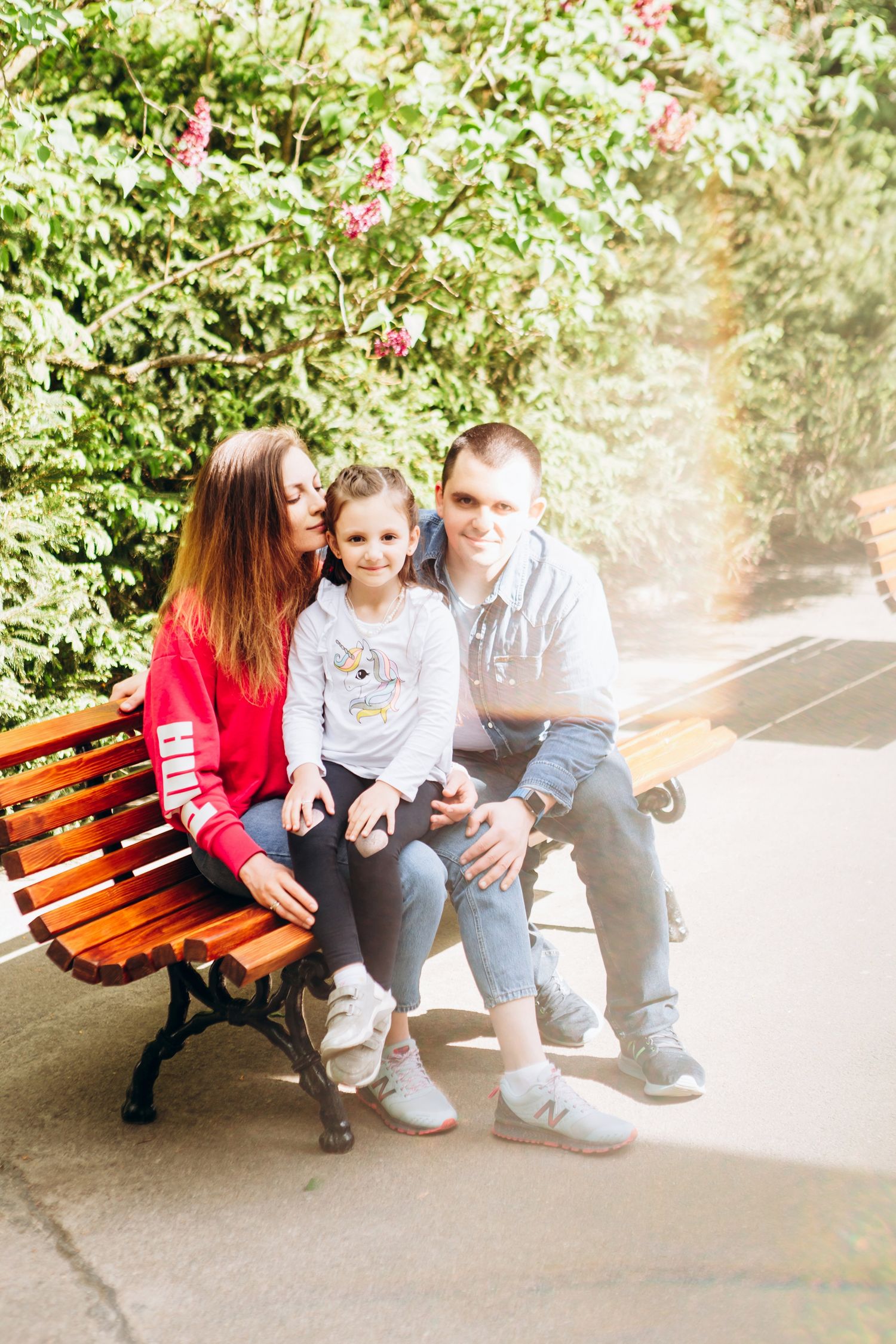 A beautiful spring day scene with a family resting on a wooden park bench.