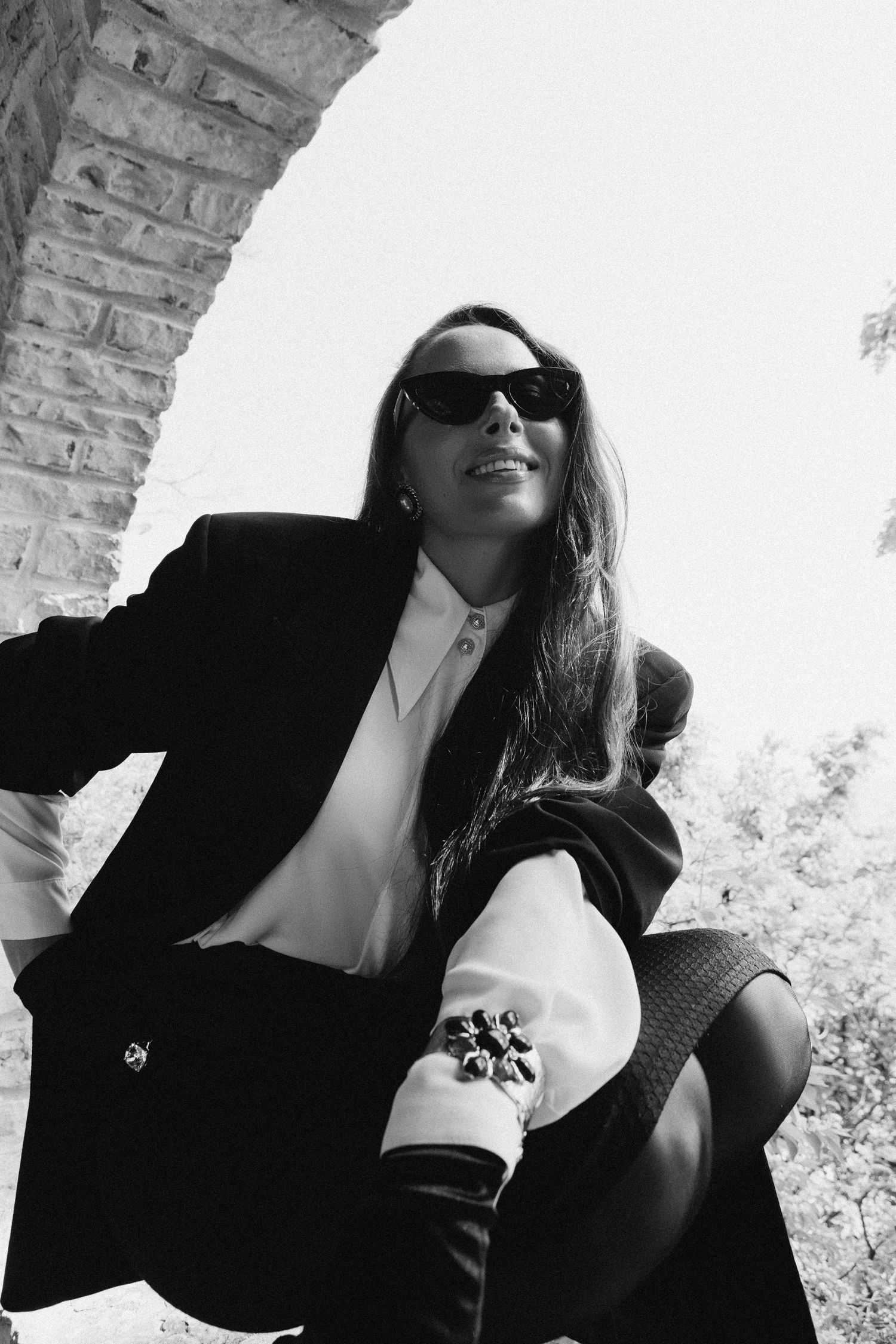 Artistic black and white portrait series showing figure in sunglasses and blazer from different dramatic angles.