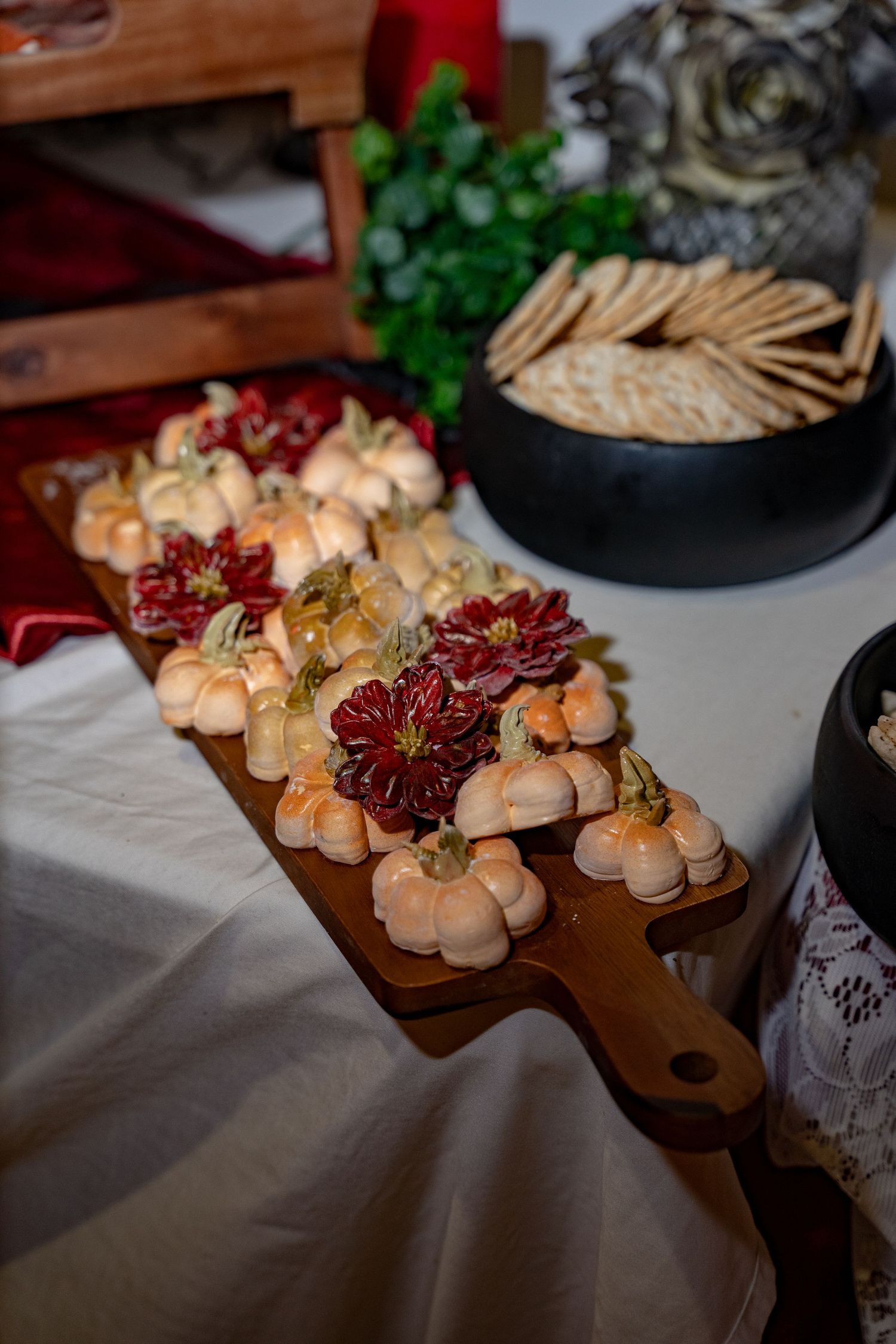 Close up of elegant party appetizers arranged on a wooden serving board with red flower garnishes.