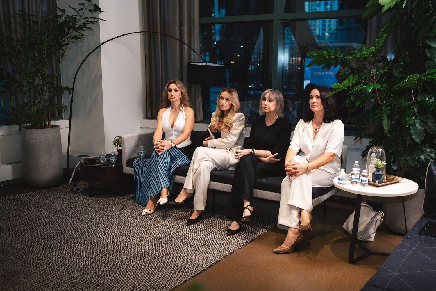 Four people sitting on modern furniture during an indoor business panel discussion.