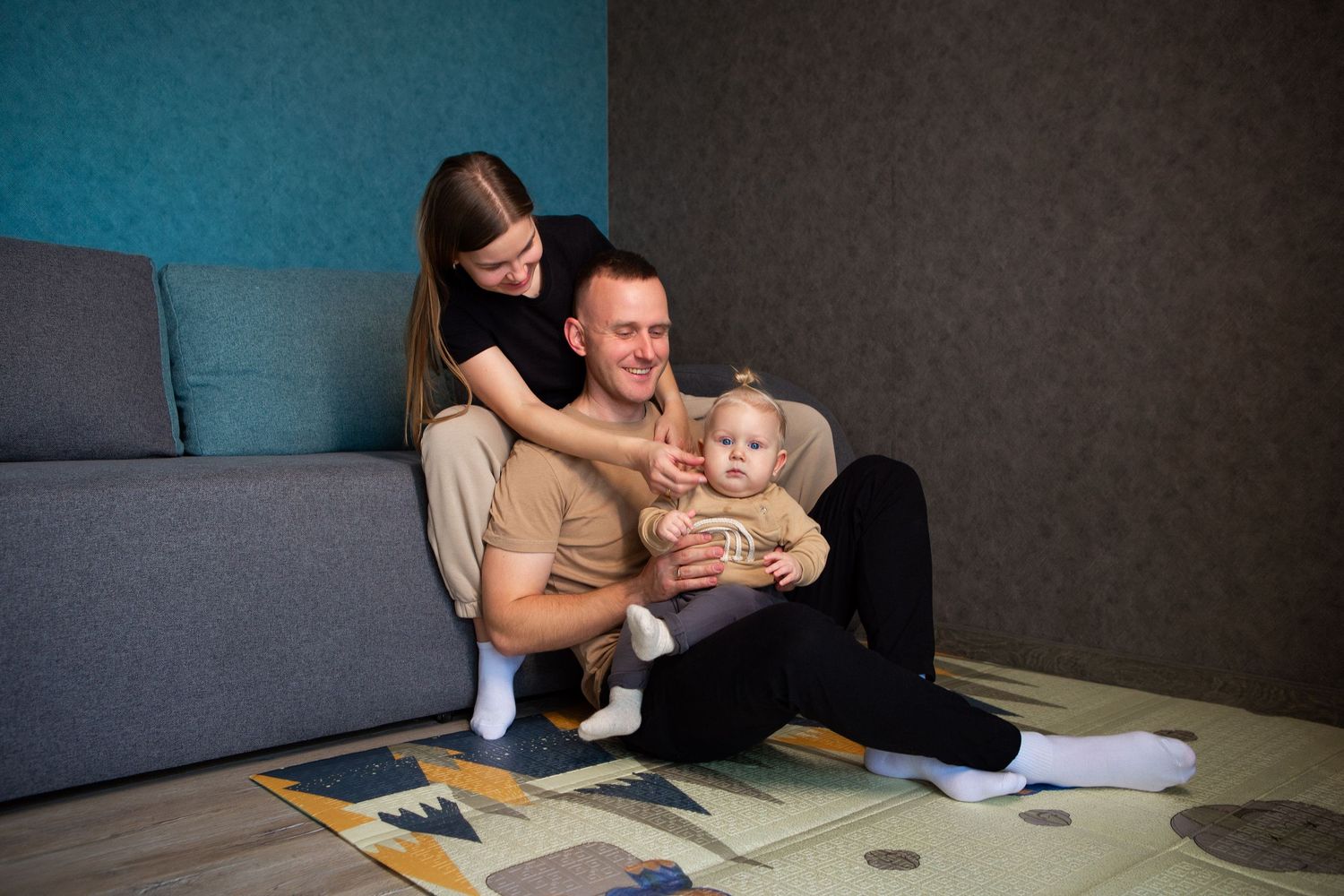 A parent and baby sit together at a desk while working from home and attending virtual meetings.