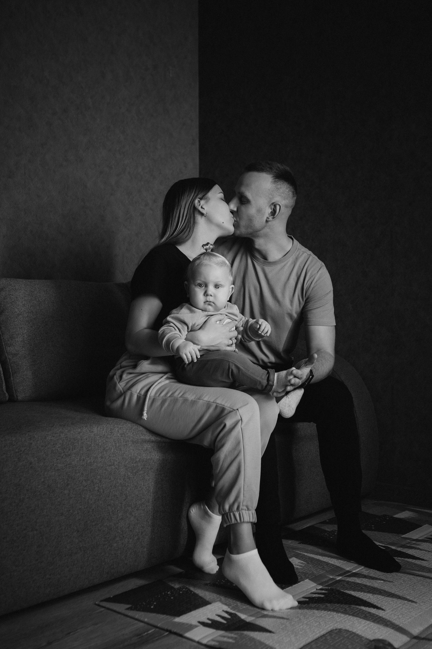 A black and white photo series shows a parent and child sitting together on a couch in different intimate poses.
