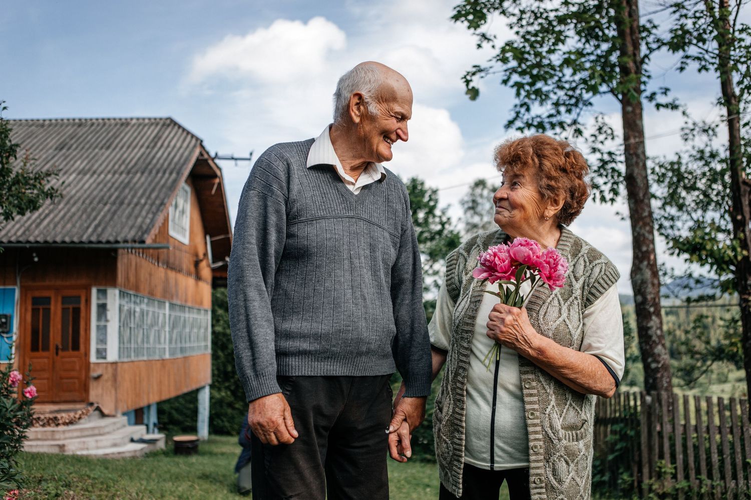 Elderly couple sharing a moment in their garden with flowers.