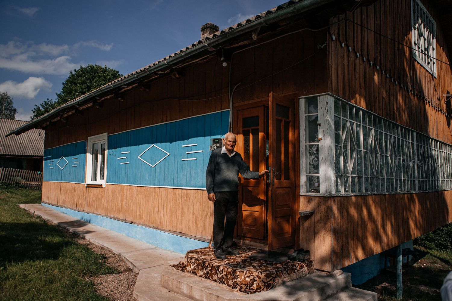 Traditional rural house with blue trim and wooden siding in countryside setting.